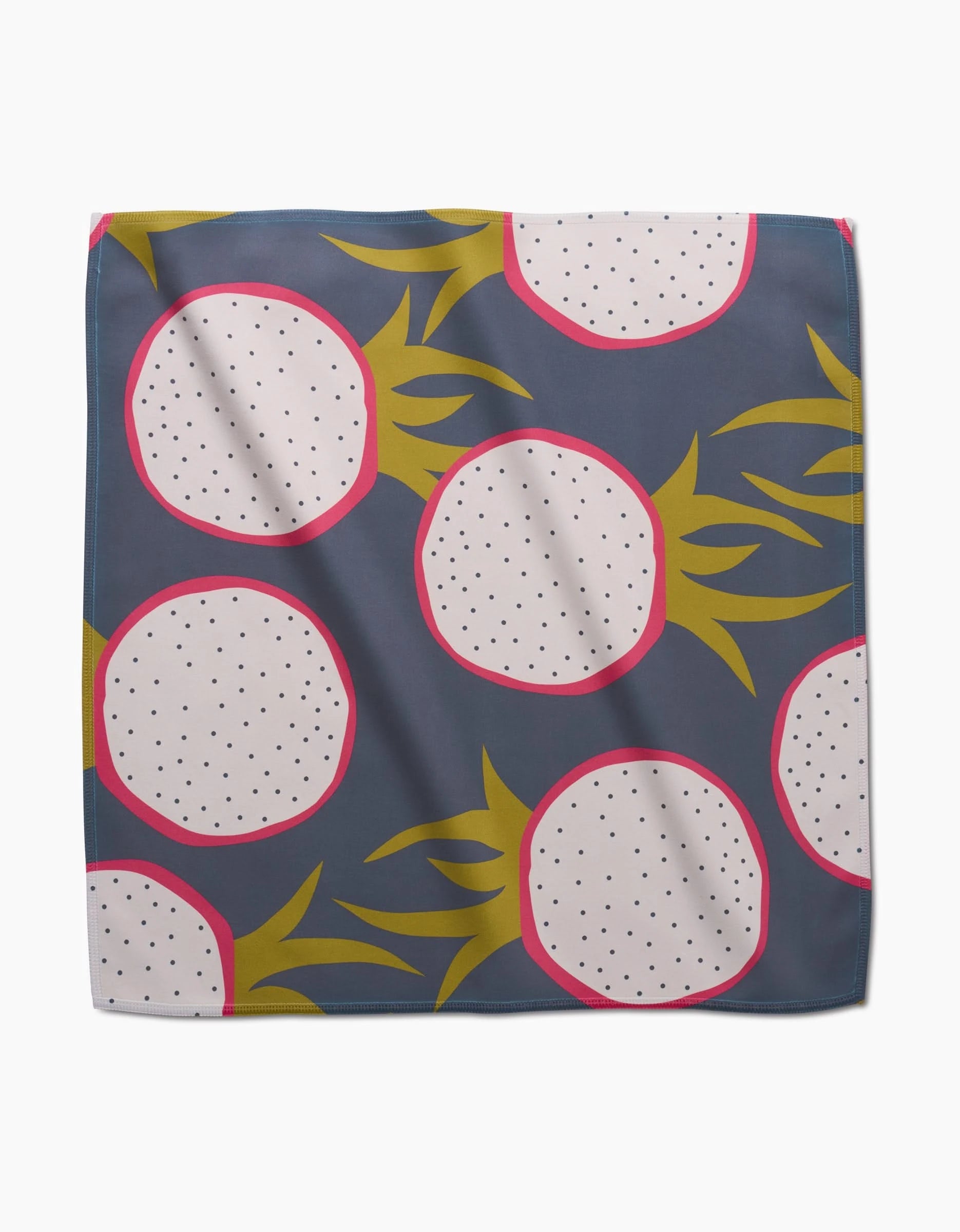 The Lizzie Clark Tropical Fruit dinner napkin set features a square Geosuede fabric with sliced dragon fruits—white flesh, black seeds, pink rinds, yellow-green leaves—on a dark gray background.