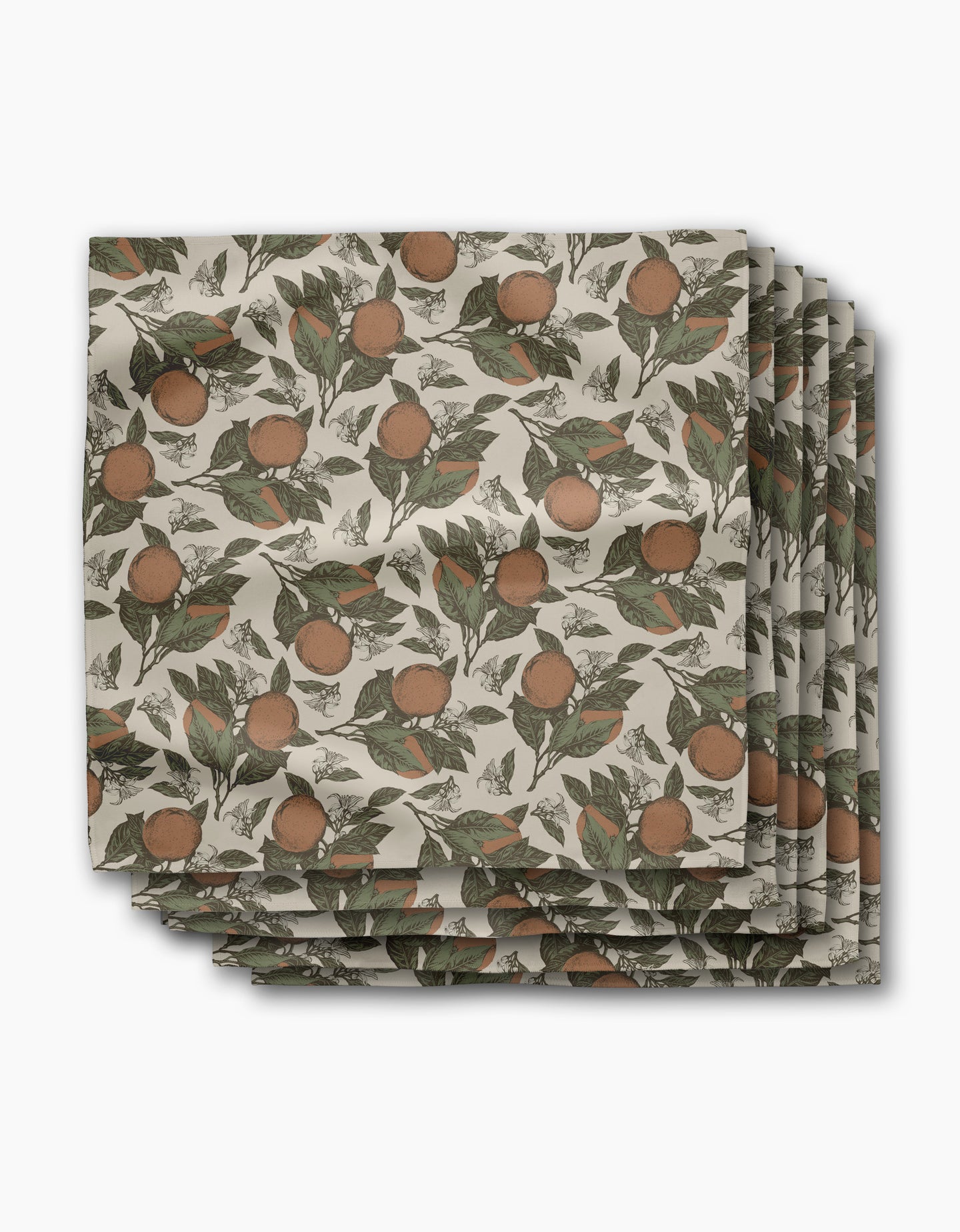 Geometry’s Valencia placemats feature a botanical orange and green leaf print on a cream background, arranged in an overlapping stack—perfect for pairing with absorbent cloth napkins for a coordinated dining table.