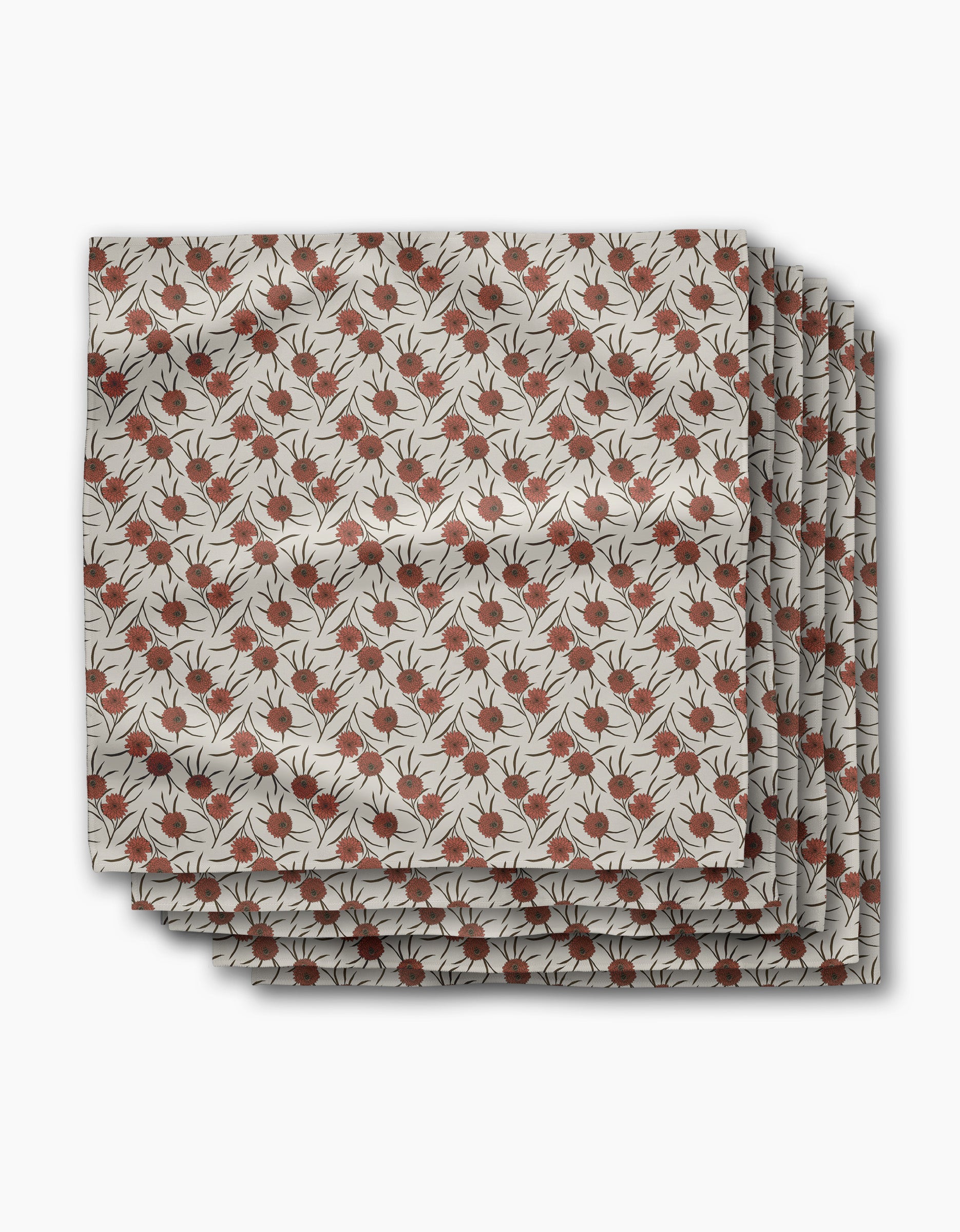 Three folded Wild Dahlia reusable dinner napkins by Geometry, featuring a repeating pattern of red pomegranates and black leafy branches on a beige background, are stacked neatly against a white backdrop.