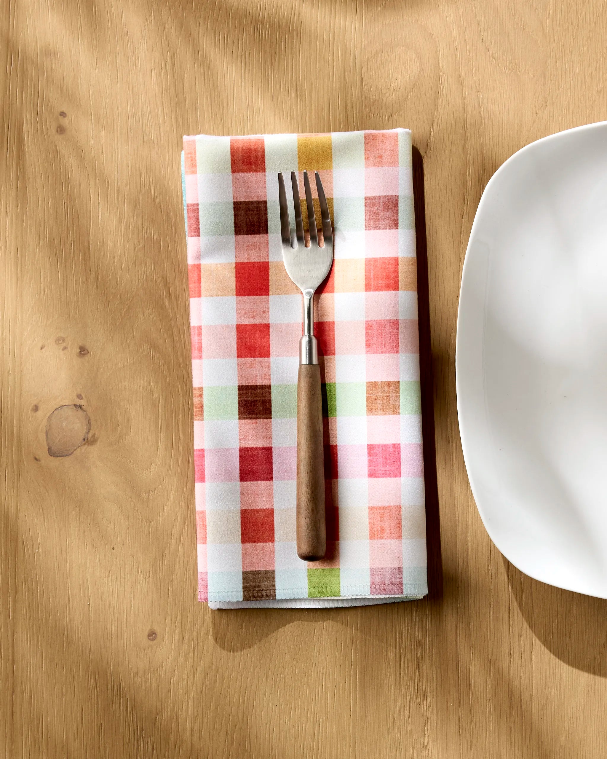 A fork rests on a Pascale Dilger Woven Spring Plaid napkin—an eco-friendly choice to elevate your tablescape.