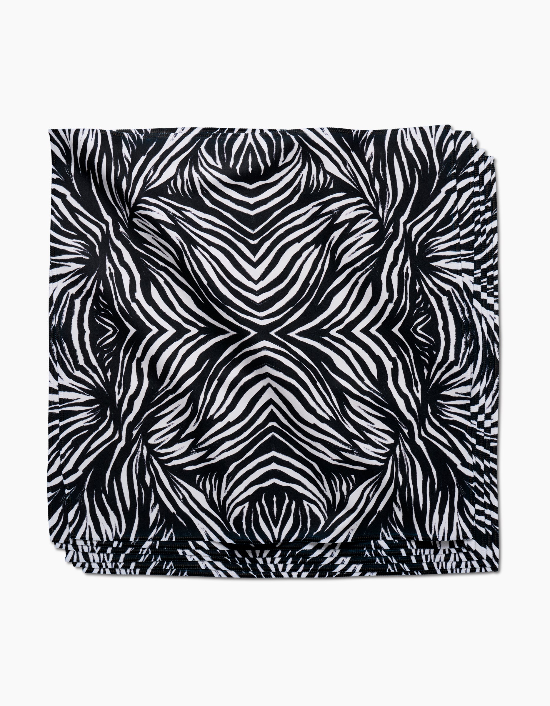 The GEOMETRY Zebra dinner napkin features a bold, symmetrical black and white zebra stripe pattern on soft Geosuede fabric, shown flat against a white background.