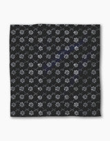 The Geometry Bonnie Indigo is a square black recycled dinner napkin featuring light gray geometric floral patterns and intersecting diamond lines, combining style and absorbency for any dinner setting.