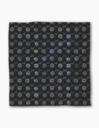 The Geometry Bonnie Indigo is a square black recycled dinner napkin featuring light gray geometric floral patterns and intersecting diamond lines, combining style and absorbency for any dinner setting.