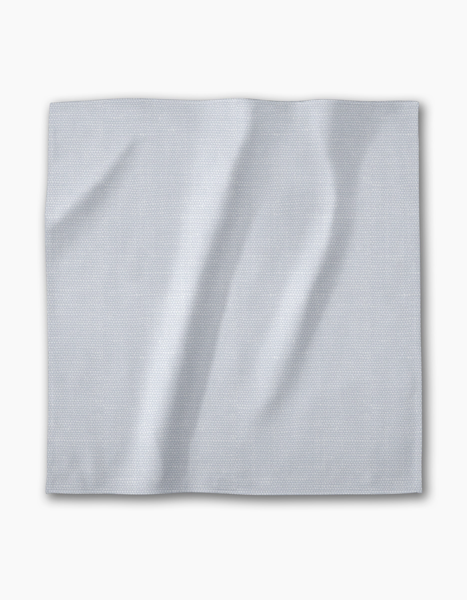 A Chambray Light Blue napkin from Geometry—a square, light gray-blue recycled fabric with a subtle textured pattern—lies flat on a white background. The absorbent cloth is part of an eco-friendly dinner napkin set.