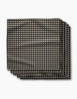 Four neatly stacked rectangular Charcoal Gingham napkins by Geometry, featuring a small black and beige check pattern, photographed on white. This eco-friendly Dinner Napkin Set is crafted from recycled materials for sustainable dining.