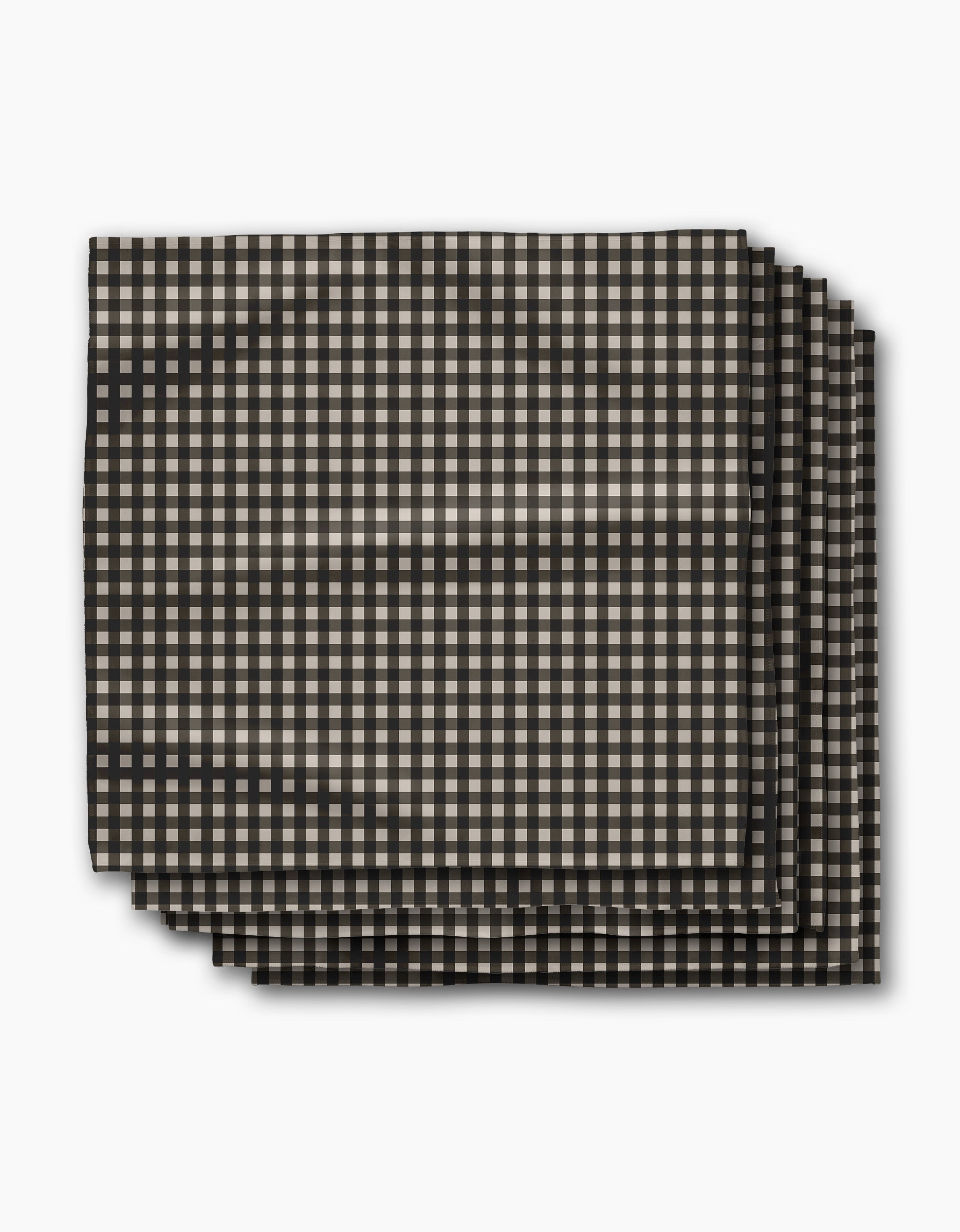 Four neatly stacked rectangular Charcoal Gingham napkins by Geometry, featuring a small black and beige check pattern, photographed on white. This eco-friendly Dinner Napkin Set is crafted from recycled materials for sustainable dining.