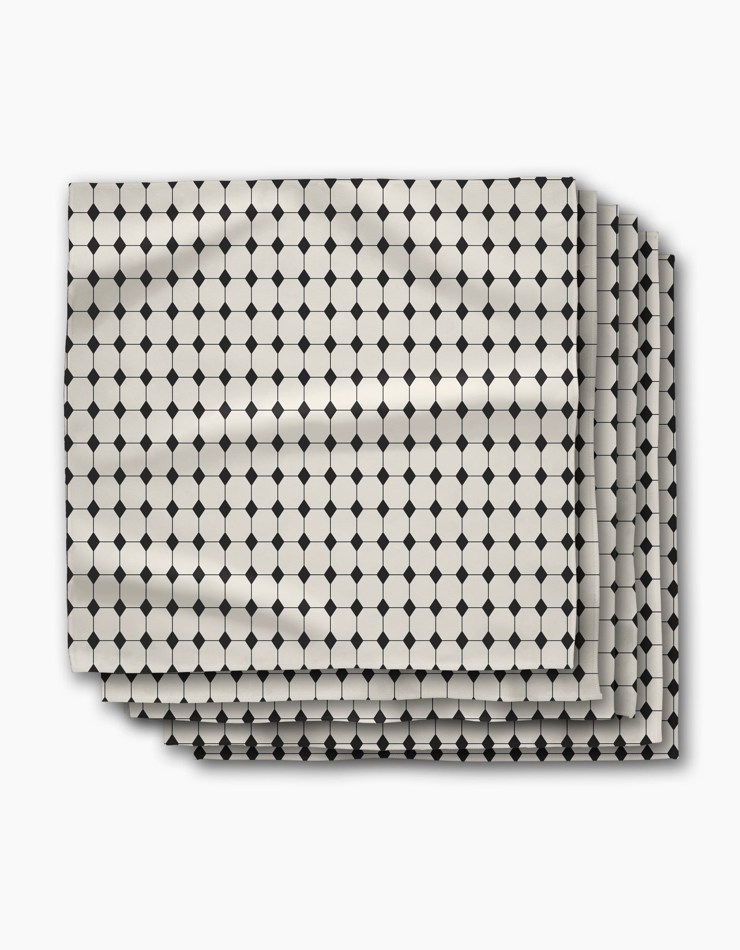 Three folded sheets from Geometry’s Espresso Mosaic collection, featuring a geometric pattern of small black circles connected by lines on cream, displayed on white—ideal as reusable napkins for stylish table settings.