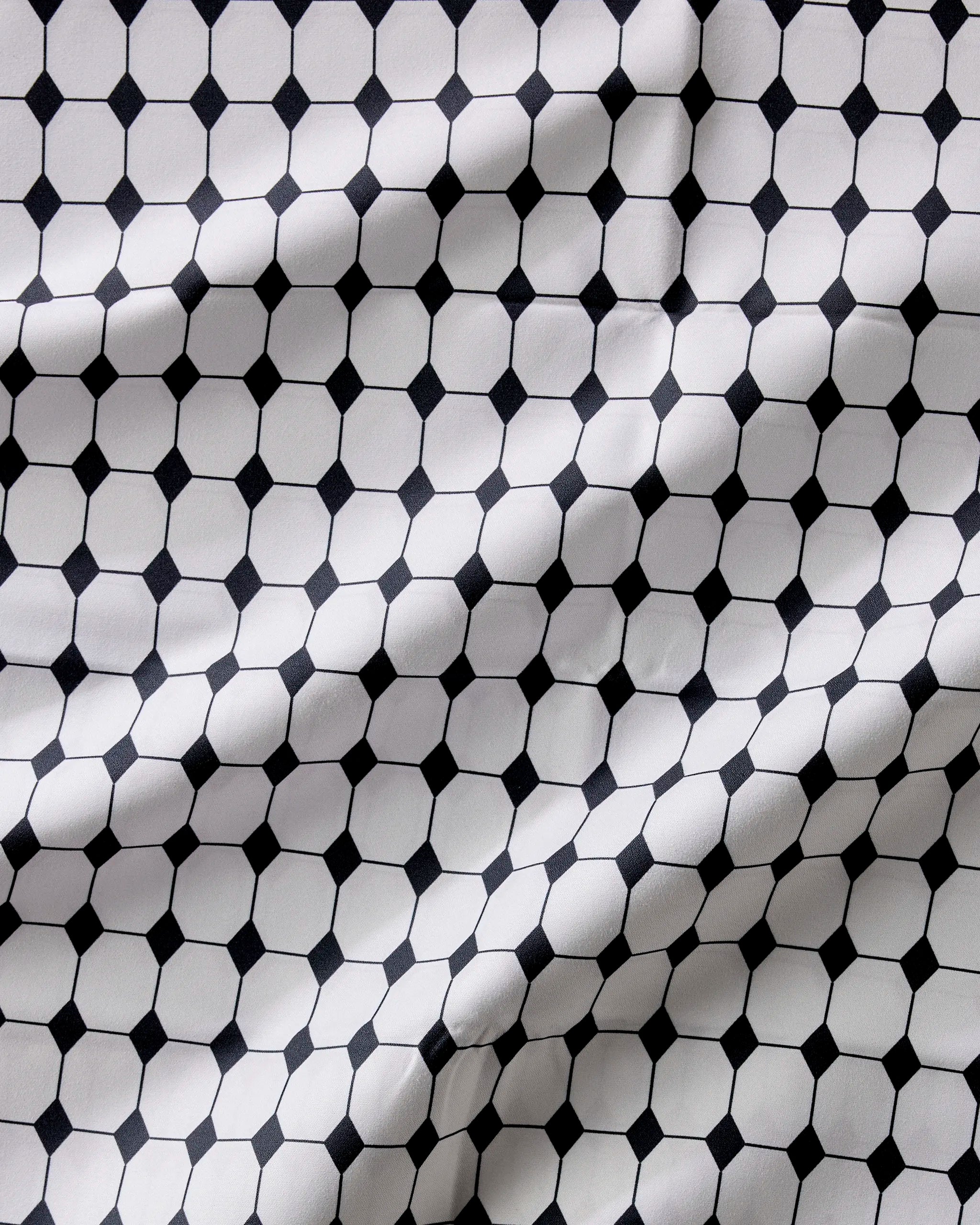 The Geometry Espresso Mosaic features a black and white hexagon and small square pattern with visible folds—an absorbent, stylish, and practical dinner napkins set.