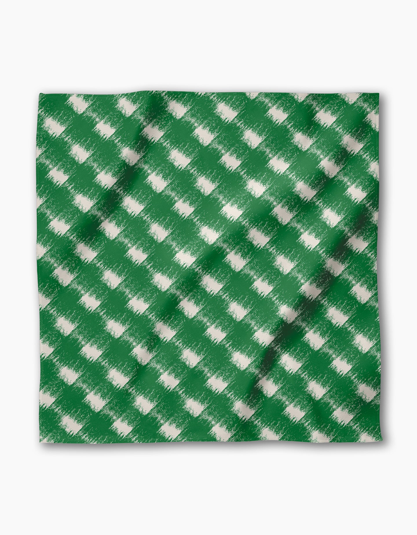 The Geometry Hairy Check Green is a reusable napkin made from recycled materials, featuring a green, square cloth with a white brushed, diagonal check pattern. It has slight folds and shadows, set against a plain white background.