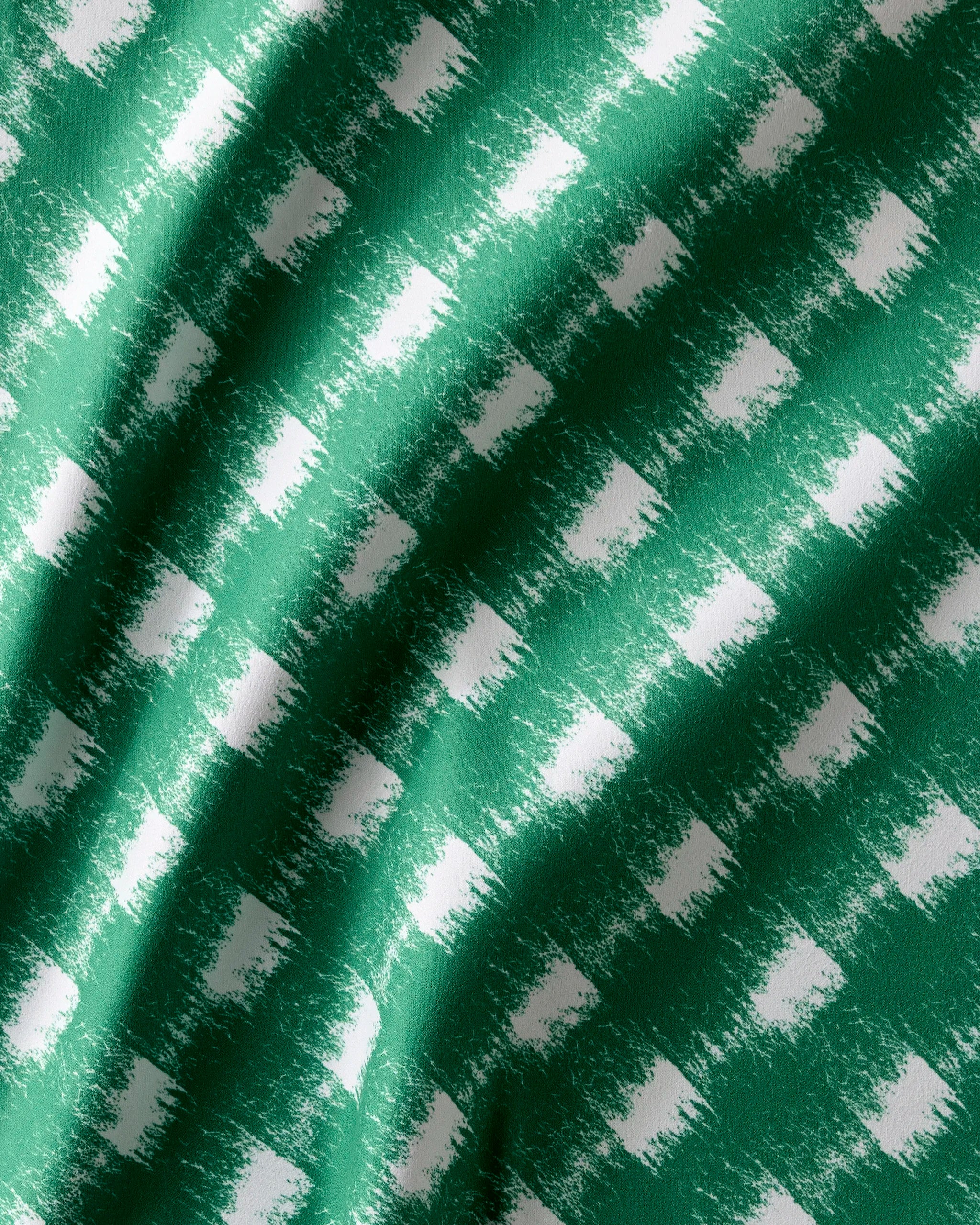 The Geometry "Hairy Check Green" napkins feature a green and white checkered, painterly pattern with visible folds and shadows that highlight their soft, textured feel.