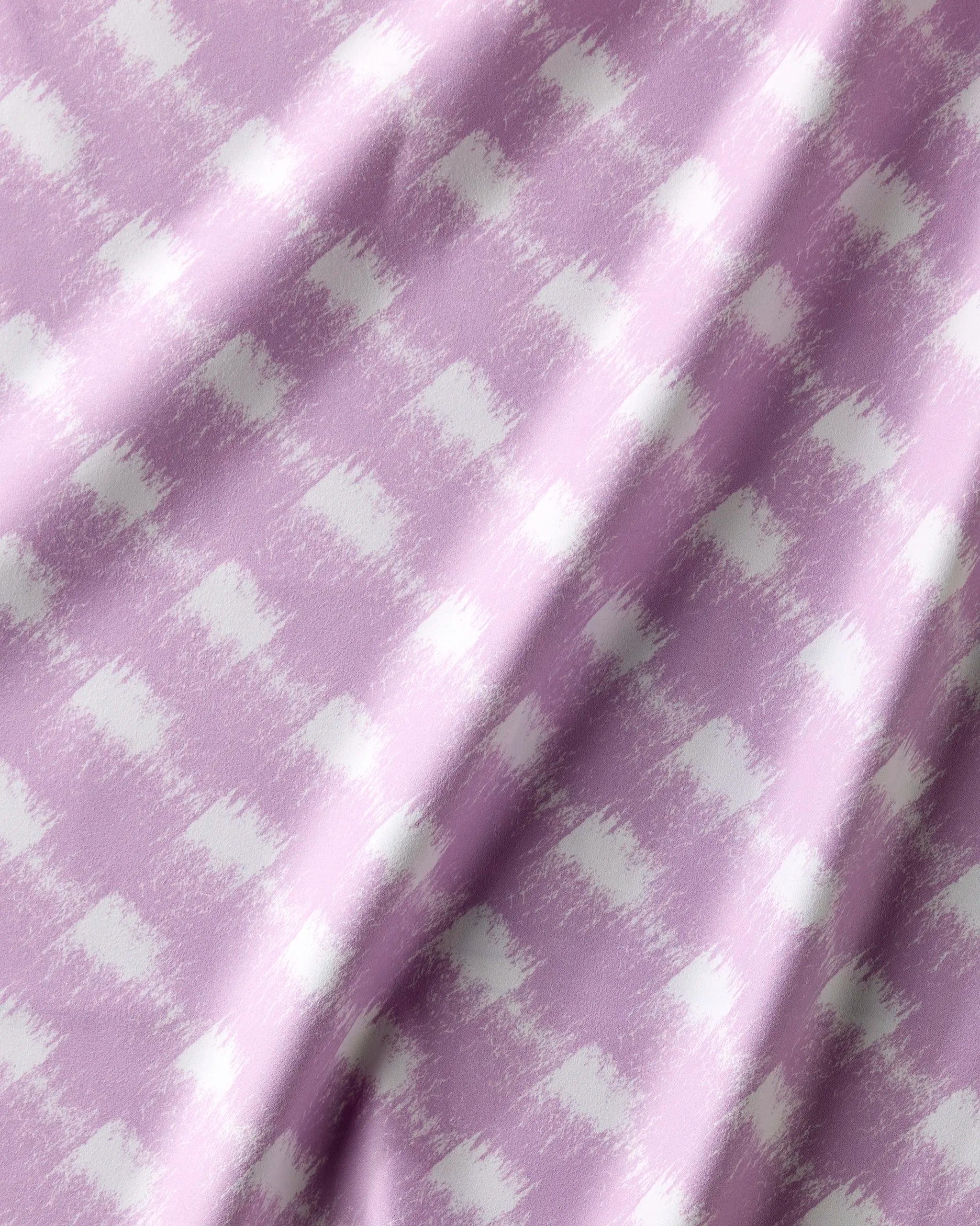 A close-up of Geometry's Hairy Check Pink fabric shows a light purple and white check pattern with a textured brushstroke effect—perfect for recycled napkins or a Dinner Napkin Set. Soft folds add cozy appeal.