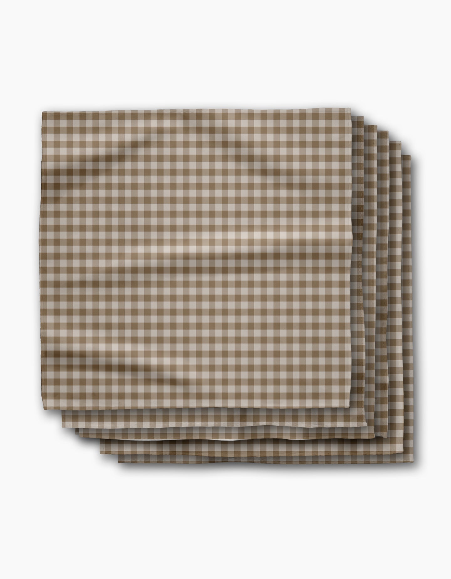 Four folded Geometry Hazel Gingham reusable napkins, featuring a brown and white checkered pattern, are neatly stacked on a white background with gentle creases.