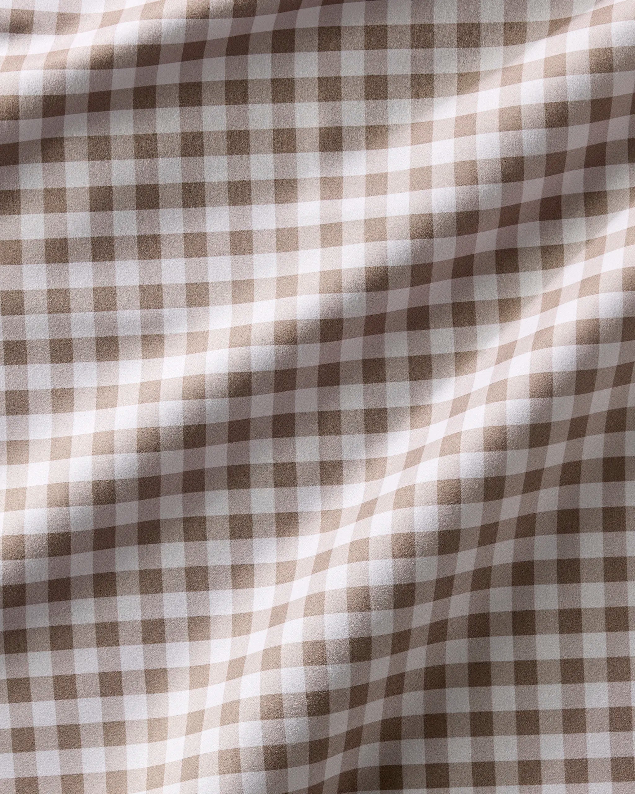 A close-up of Hazel Gingham by Geometry displays its beige and white checkered Geosuede fabric with gentle folds and soft shadows—ideal for recycled dinner napkins or a Dinner Napkin Set.