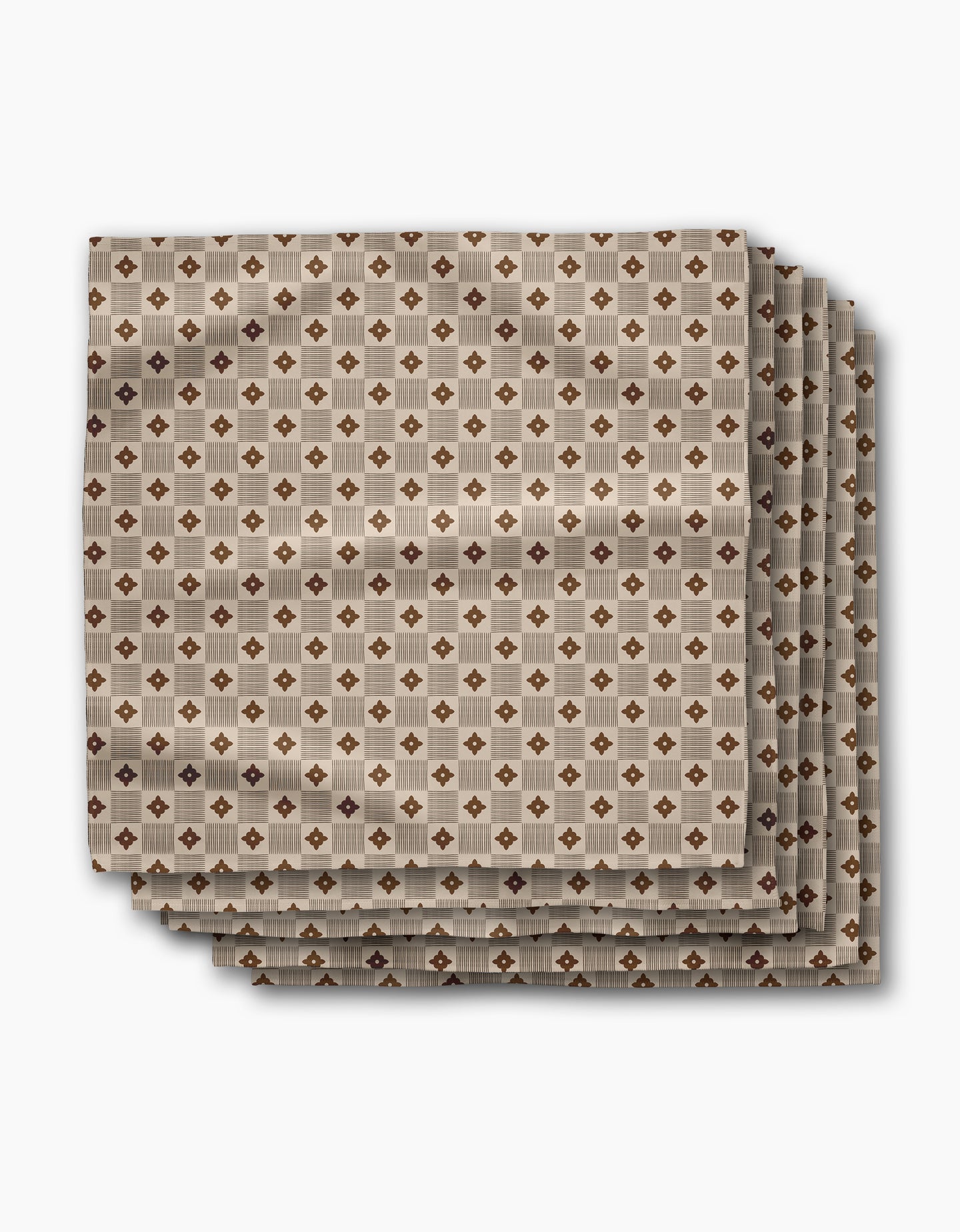 Four absorbent dinner napkins from Geometry’s Heritage Stamp collection feature a geometric brown and beige diamond pattern, neatly folded and displayed on a white background—perfect for adding style to your table.