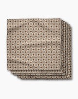 Four absorbent dinner napkins from Geometry’s Heritage Stamp collection feature a geometric brown and beige diamond pattern, neatly folded and displayed on a white background—perfect for adding style to your table.