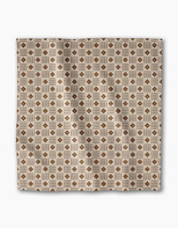 The Heritage Stamp dinner napkin set by Geometry features a square beige fabric with a geometric pattern of brown diamonds and tan squares. Made from recycled materials, these eco-friendly napkins bring style to your table setting.