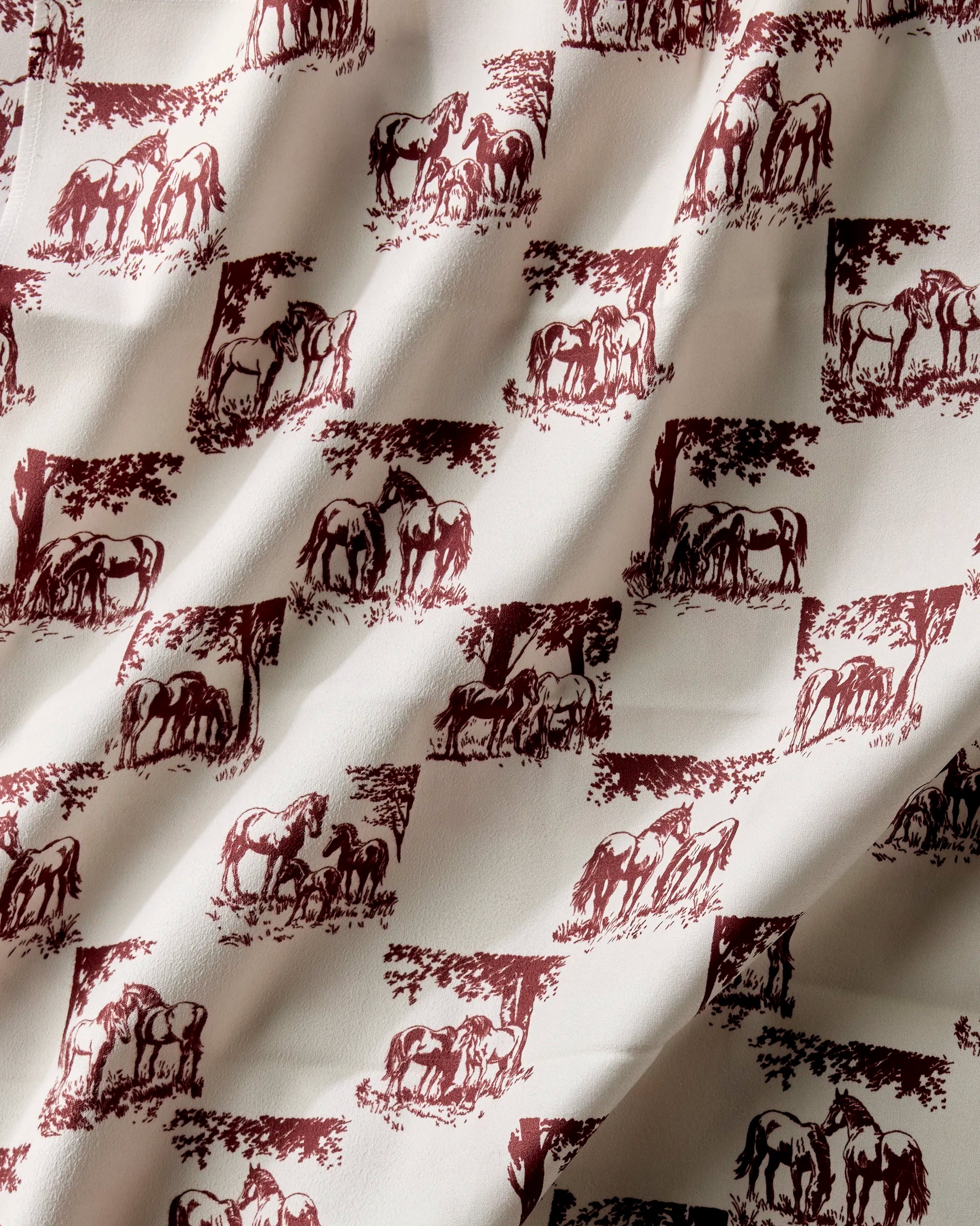 Geometry’s Horse Check Cream washable napkin set features a cream-colored fabric with maroon horse and tree motifs. Made from recycled materials, these napkins drape softly and bring charm to your table.