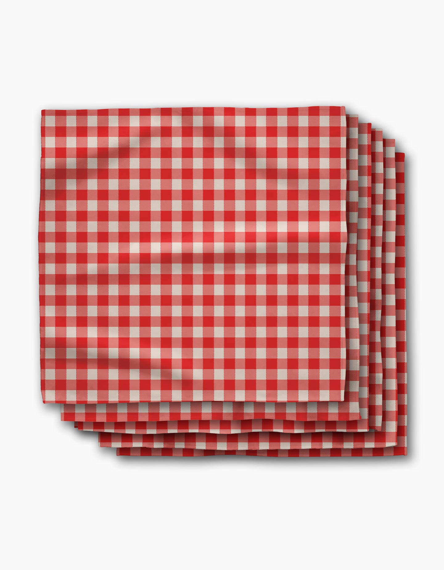 Four folded Ripe Tomato Gingham napkins by Geometry, featuring a red and white checkered pattern, are stacked neatly on a white background. Made from Geosuede fabric, this set blends softness with sustainable style.
