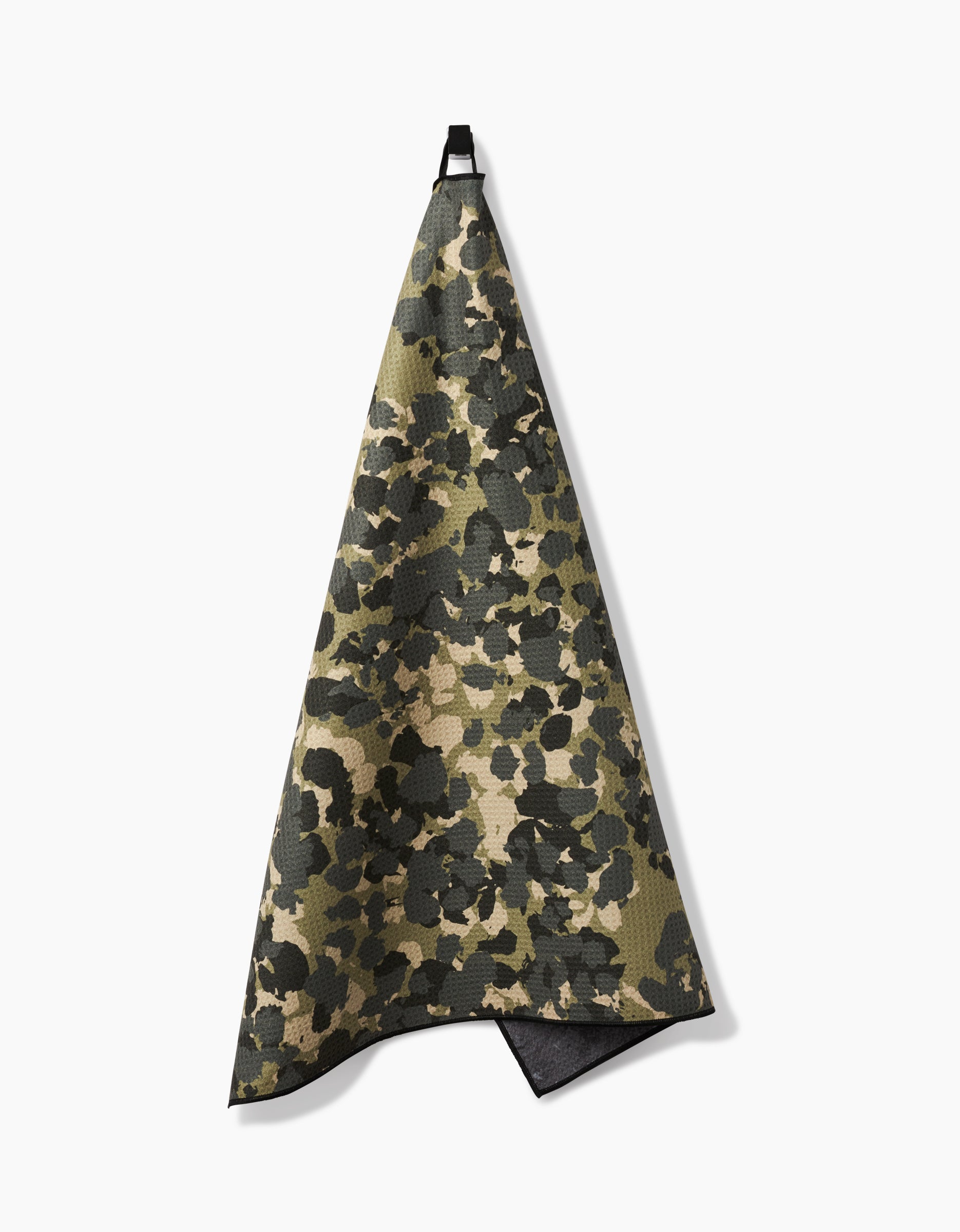 The Geometry Camo dog towel features a camouflage pattern in green, brown, and beige, is absorbent, and hangs by a black loop against a white background.