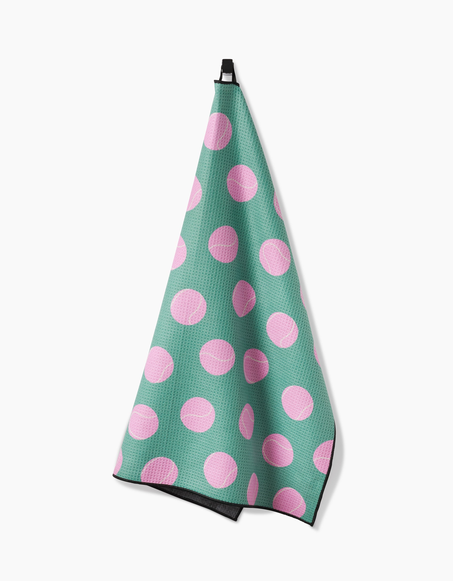 The Geometry Pink Ball towel, known for high absorbency, features large pink polka dots on green fabric and hangs from a black hook against a white background.