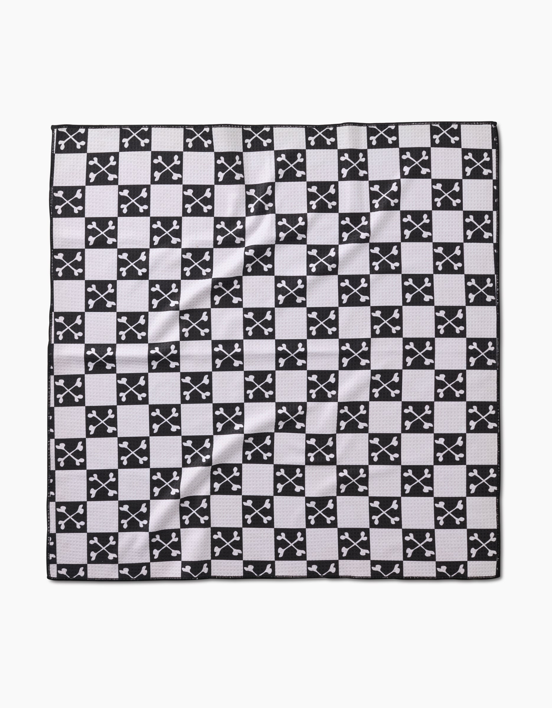 The Boneyard Black Checkerboard by Charlie Rowan Designs is a square dog towel made from recycled materials, featuring a black and white checkerboard pattern with crossed-swords emblems and a textured, eco-friendly feel.