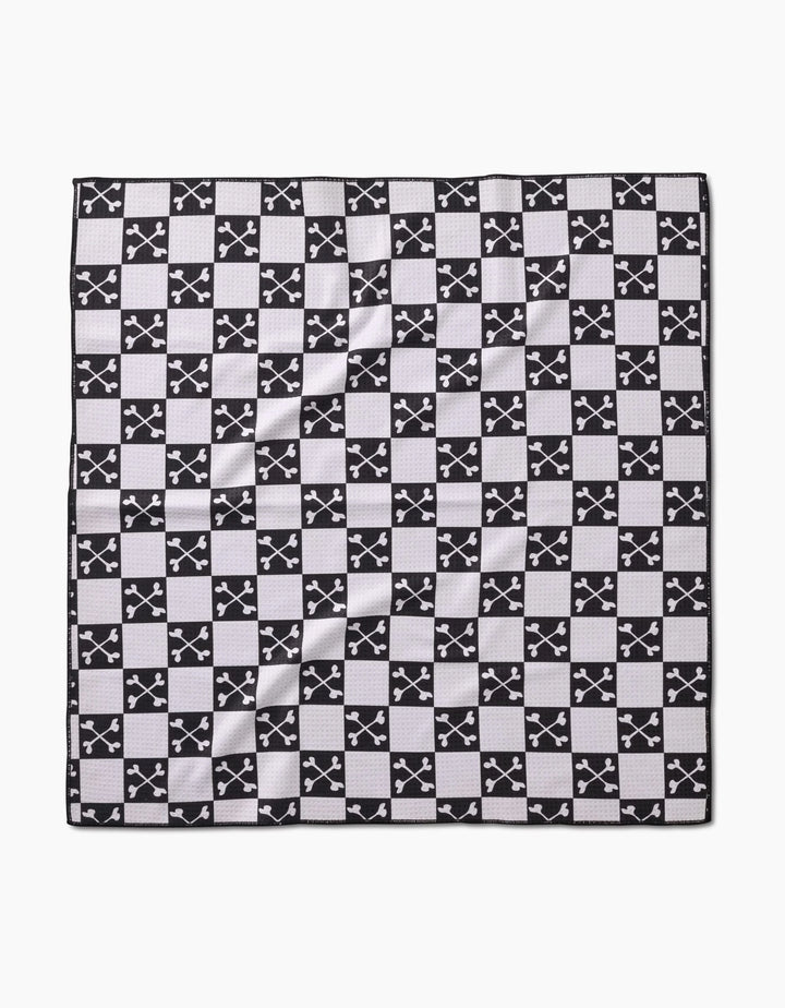 The Boneyard Black Checkerboard by Charlie Rowan Designs is a square dog towel made from recycled materials, featuring a black and white checkerboard pattern with crossed-swords emblems and a textured, eco-friendly feel.