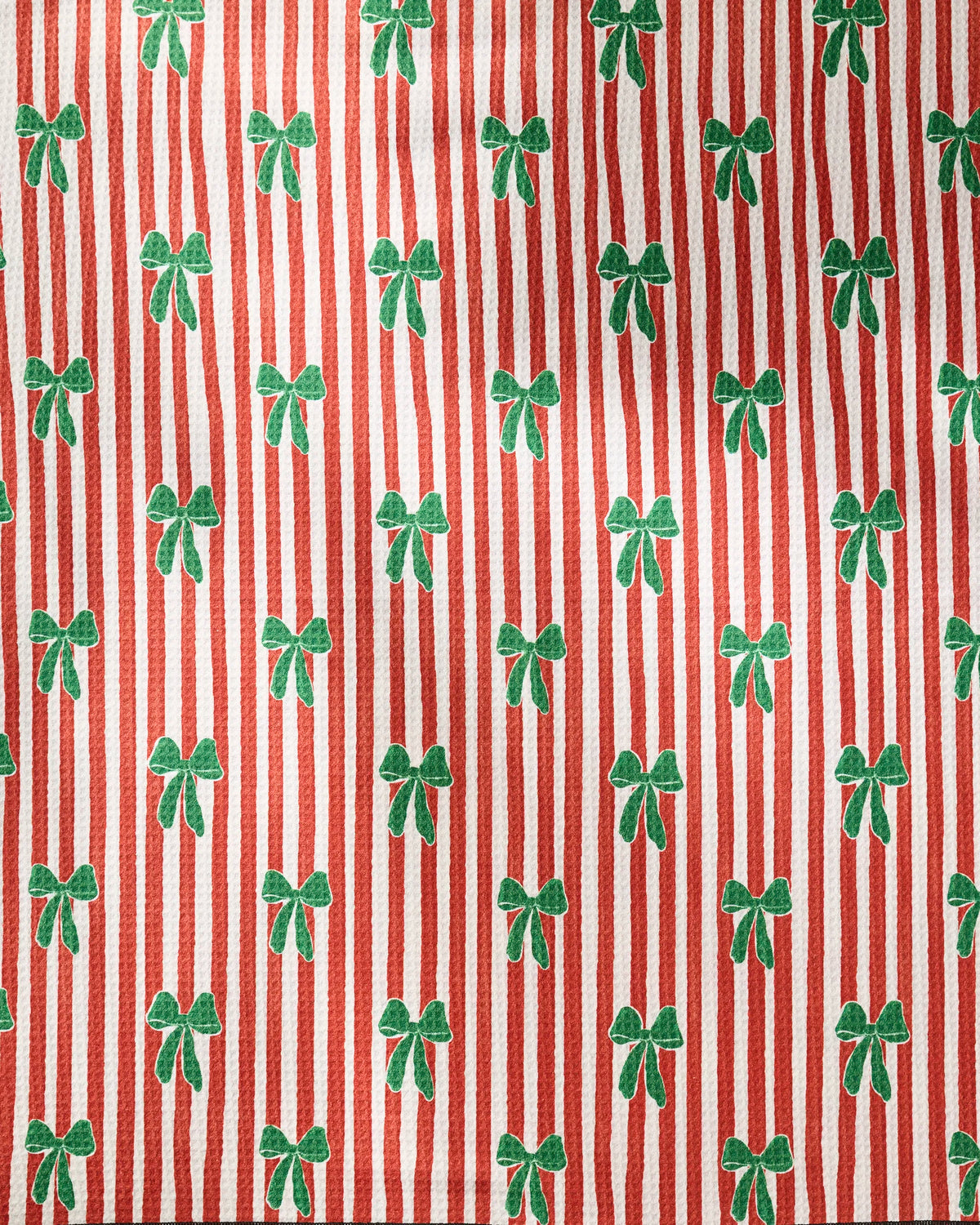 Candy Bows by Geometry features a red and white vertical striped fabric pattern with green bows evenly spaced throughout. Crafted from recycled materials, this highly absorbent dog towel offers a festive, holiday-themed appearance.
