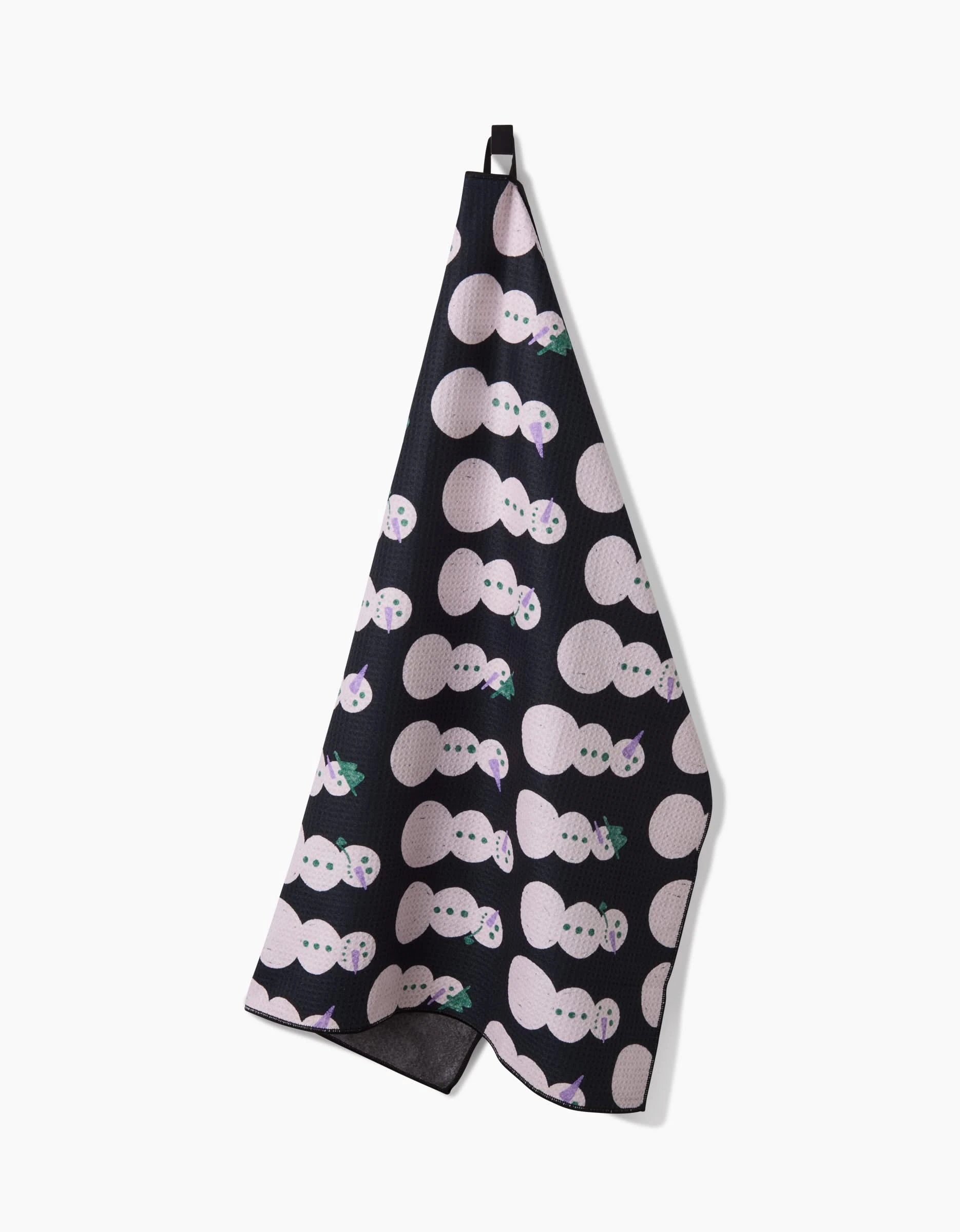 The Felicity Black tea towel by Amy MacCready is made from absorbent dog towel fabric, featuring large light pink circles with smiling faces and green leaves, and hangs from a black loop.
