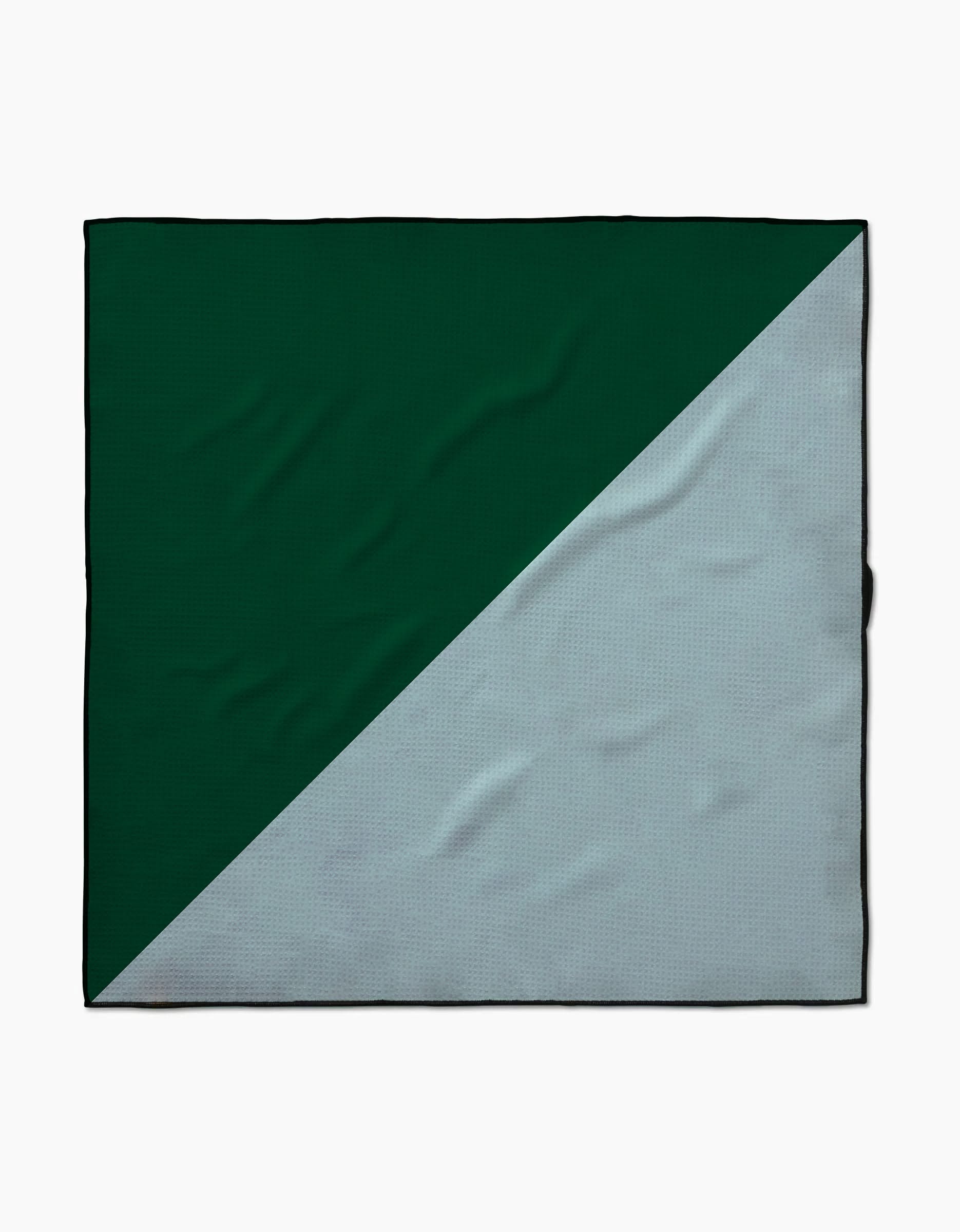 The Minted Oasis by Geometry is a square cloth made from recycled materials with a diagonal split design—dark green on the top left and light gray on the bottom right, showcasing some visible fabric wrinkles.