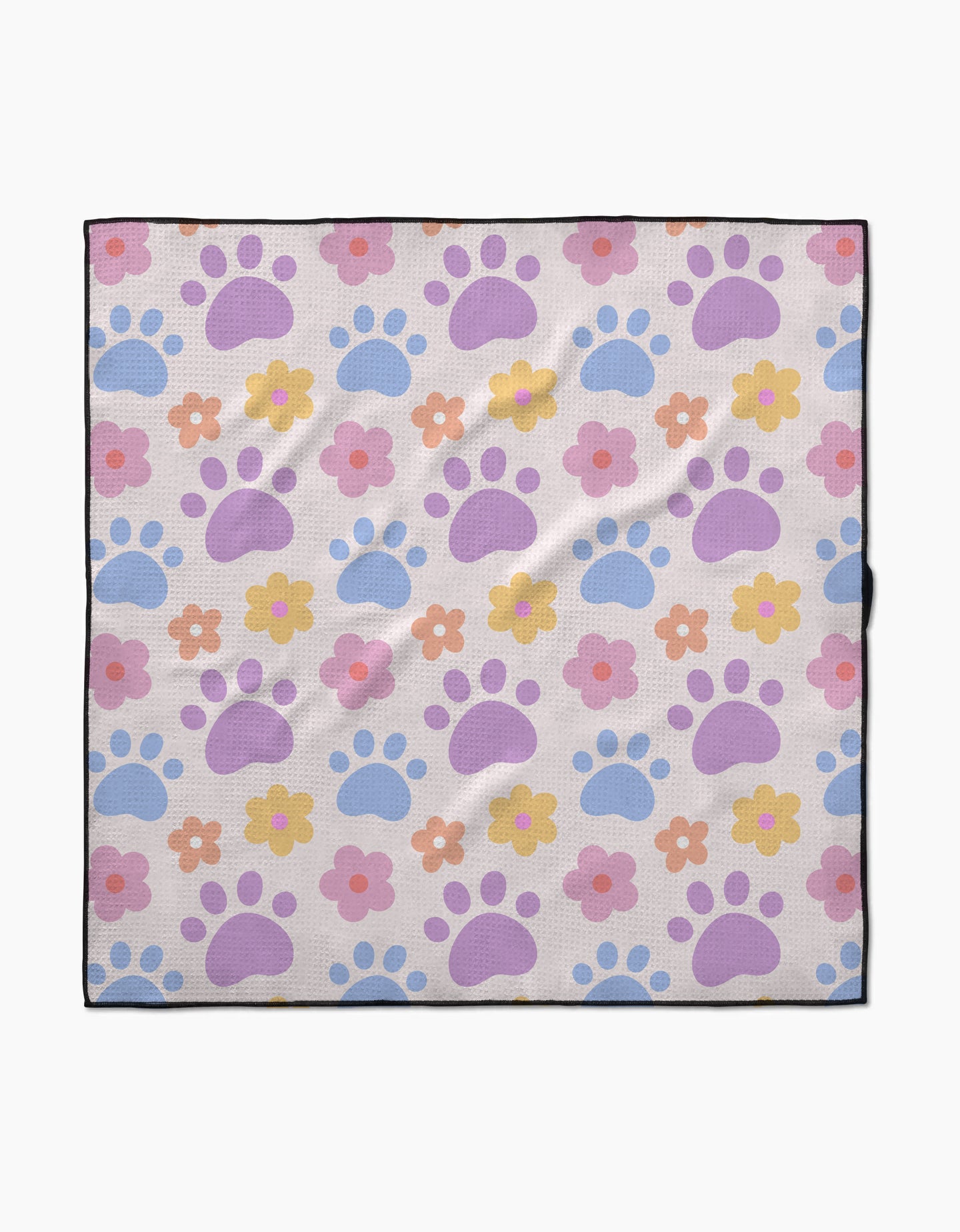The Paws and Daisies dog towel by Letters By Shells is highly absorbent, made from recycled materials, and features pastel blue and purple paw prints with pink, orange, and yellow flowers on a light background with a slim black border.
