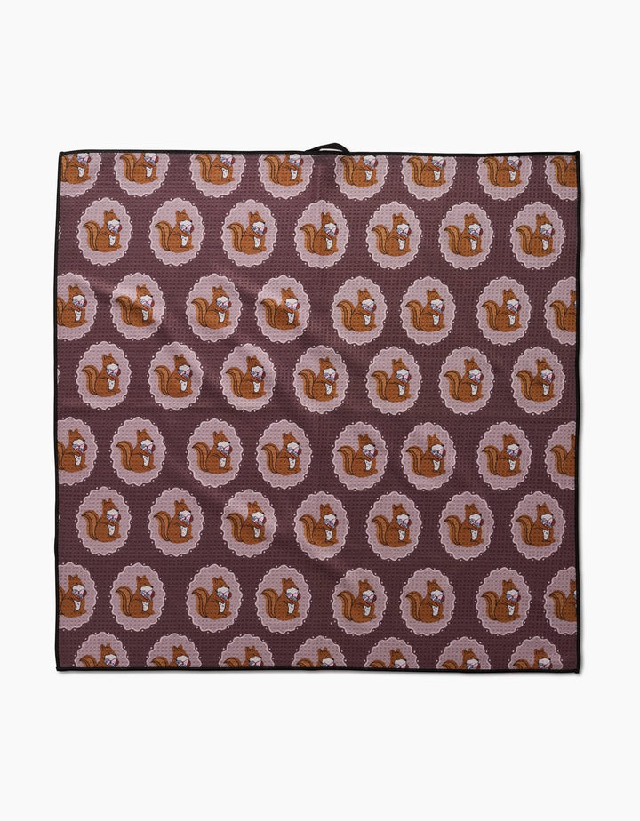 The Megan Roy Squirrels Brown mat is an eco-friendly, rectangular dog towel with a repeating pattern of brown squirrels in pink rings on a dark background. Highly absorbent and perfect for your furry friend.