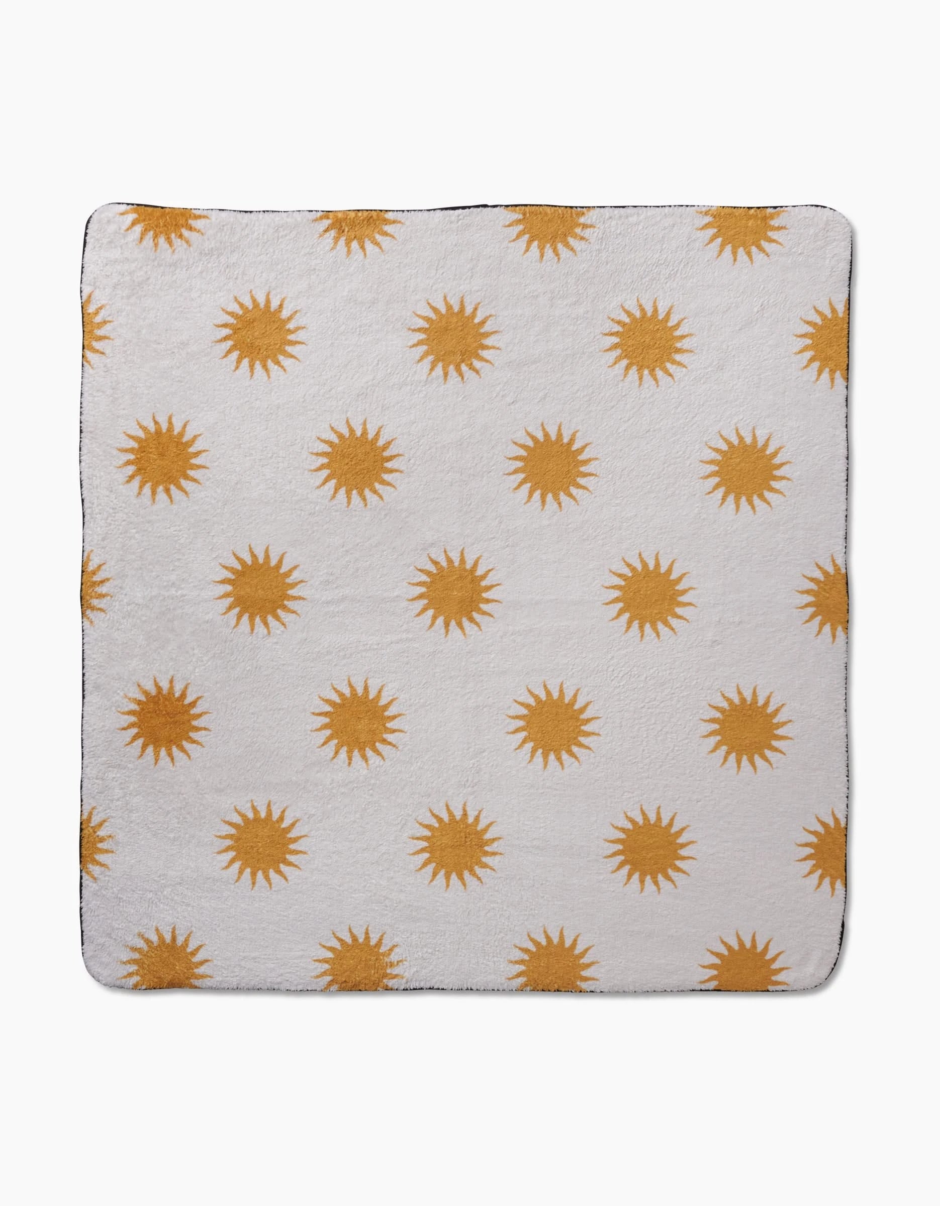 The Geometry Feeling Sunny blanket is a soft white square throw with a repeating yellow sun pattern, crafted from recycled materials for eco-friendly comfort.