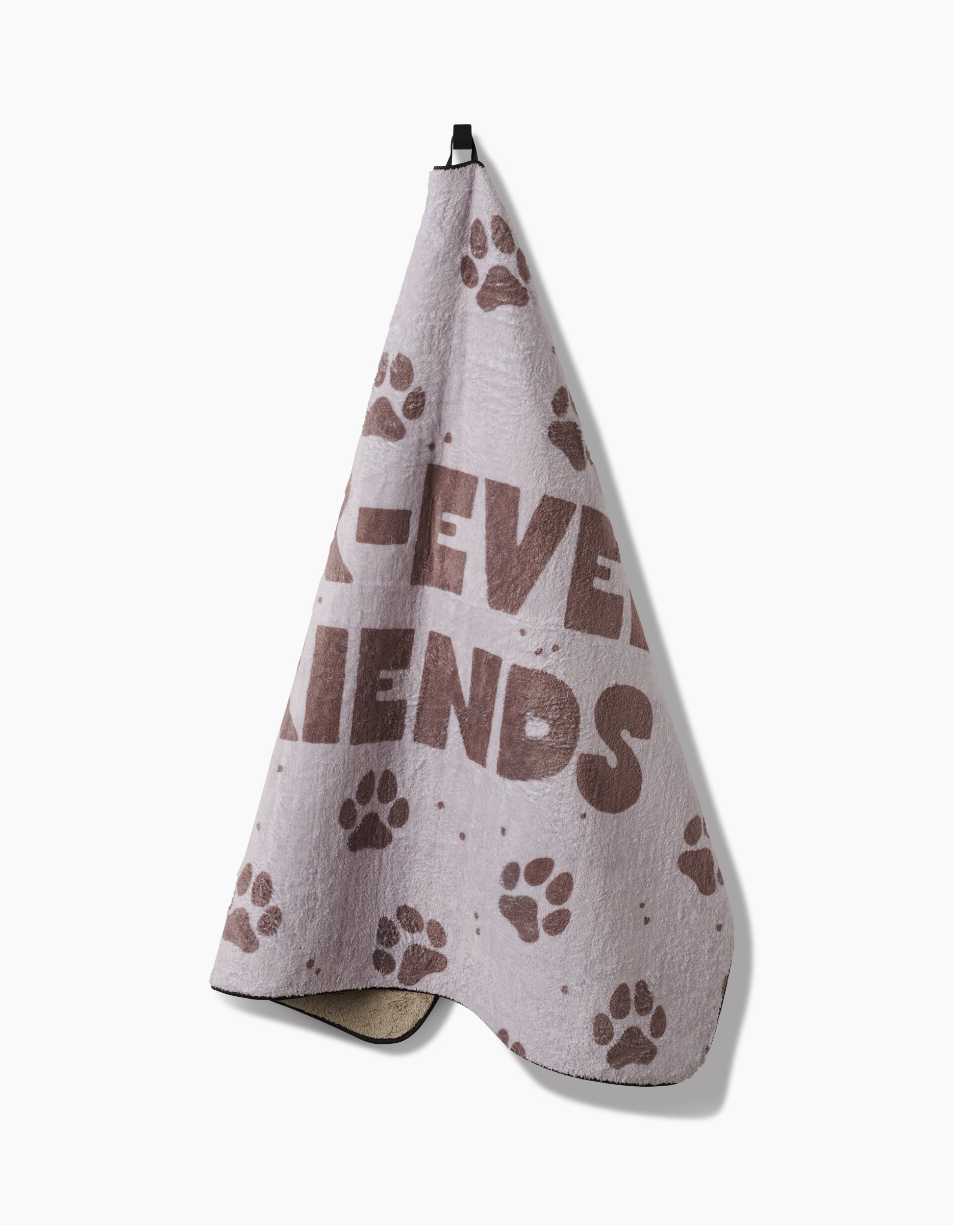 The Geometry Fur Ever Friends Plush Dog Towel features brown paw prints, partially visible “FRIENDS” text, and hangs from a black loop. Made of ultra-absorbent recycled materials for fast, sustainable drying.