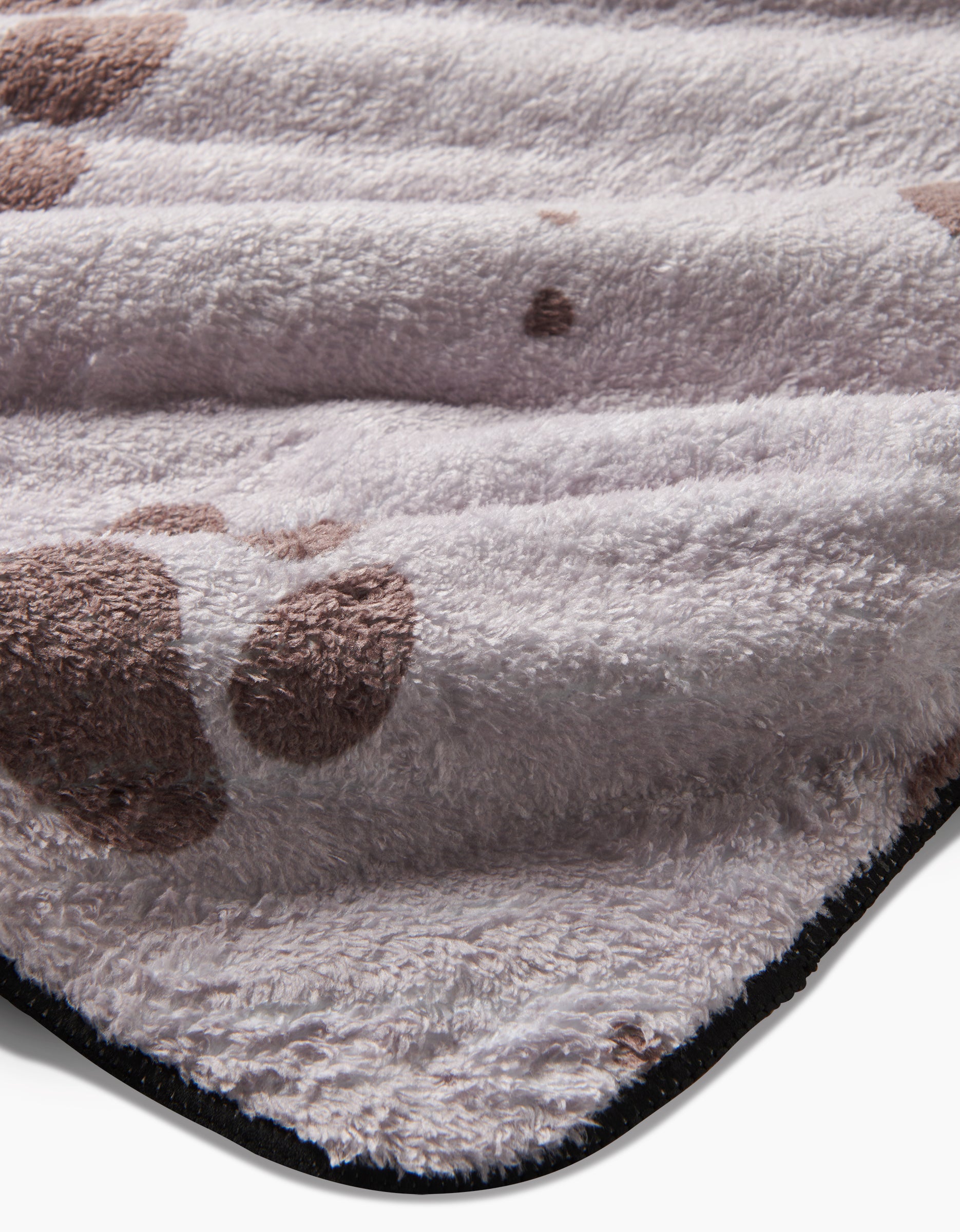 Close-up of Fur Ever Friends by Geometry: a soft, ultra-absorbent light gray fabric with brown paw prints and black edge trim, likely from a plush dog towel or mat made with recycled materials.