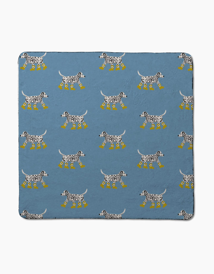 The Geometry Dalmatian In Boots Blue blanket features a pattern of black-and-white dogs in yellow boots, crafted from ultra-absorbent recycled materials.