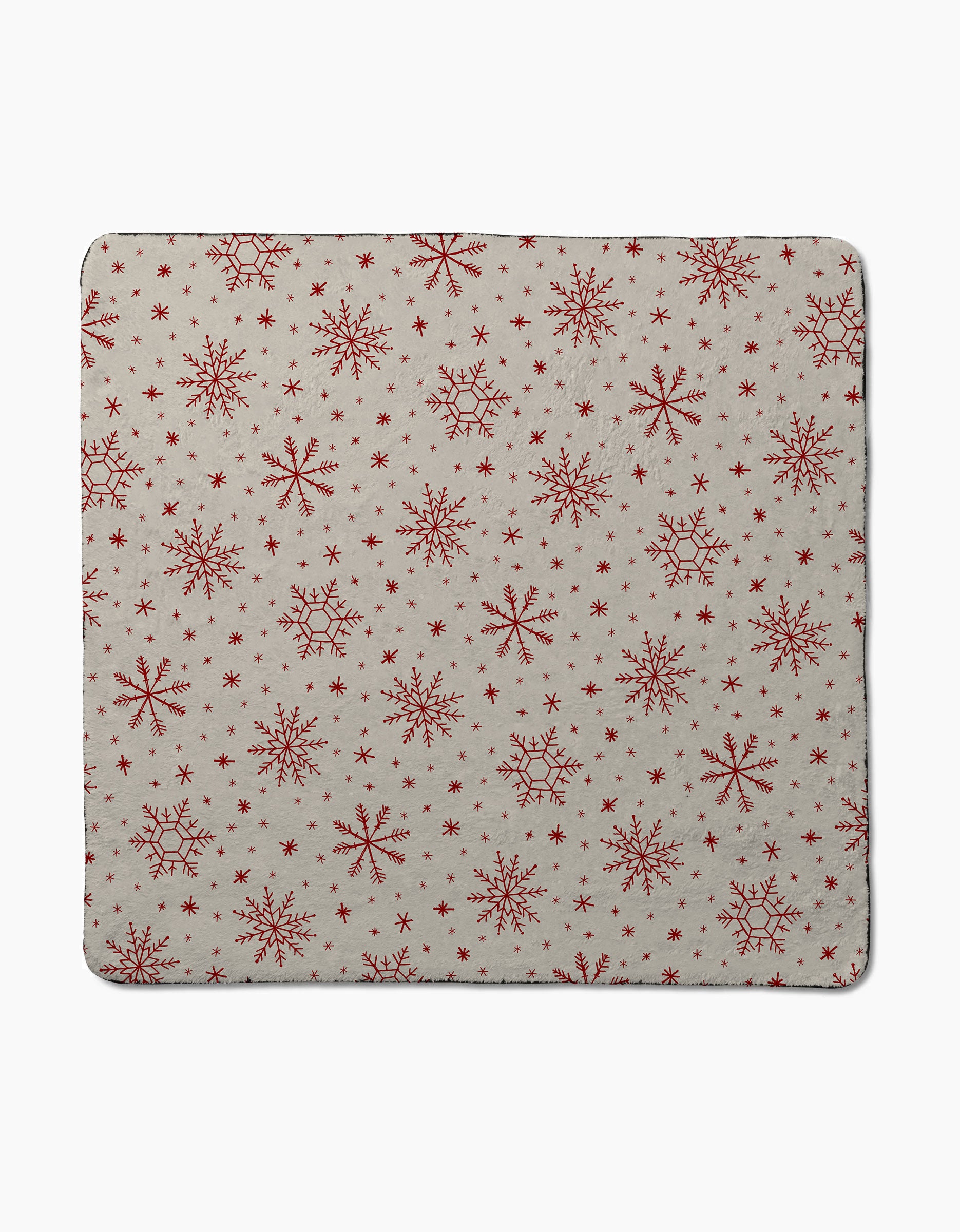 Firlight Red by Geometry is a square napkin made from recycled dog towel material, featuring a beige background with red snowflakes in various sizes for a festive, wintry look.