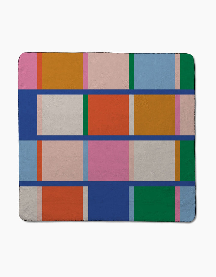 Grid by Jennifer Bouron is a rectangular, ultra-absorbent blanket with a geometric pattern of colorful rectangles and squares—orange, pink, blue, green, and gray—outlined by bold blue and purple lines.