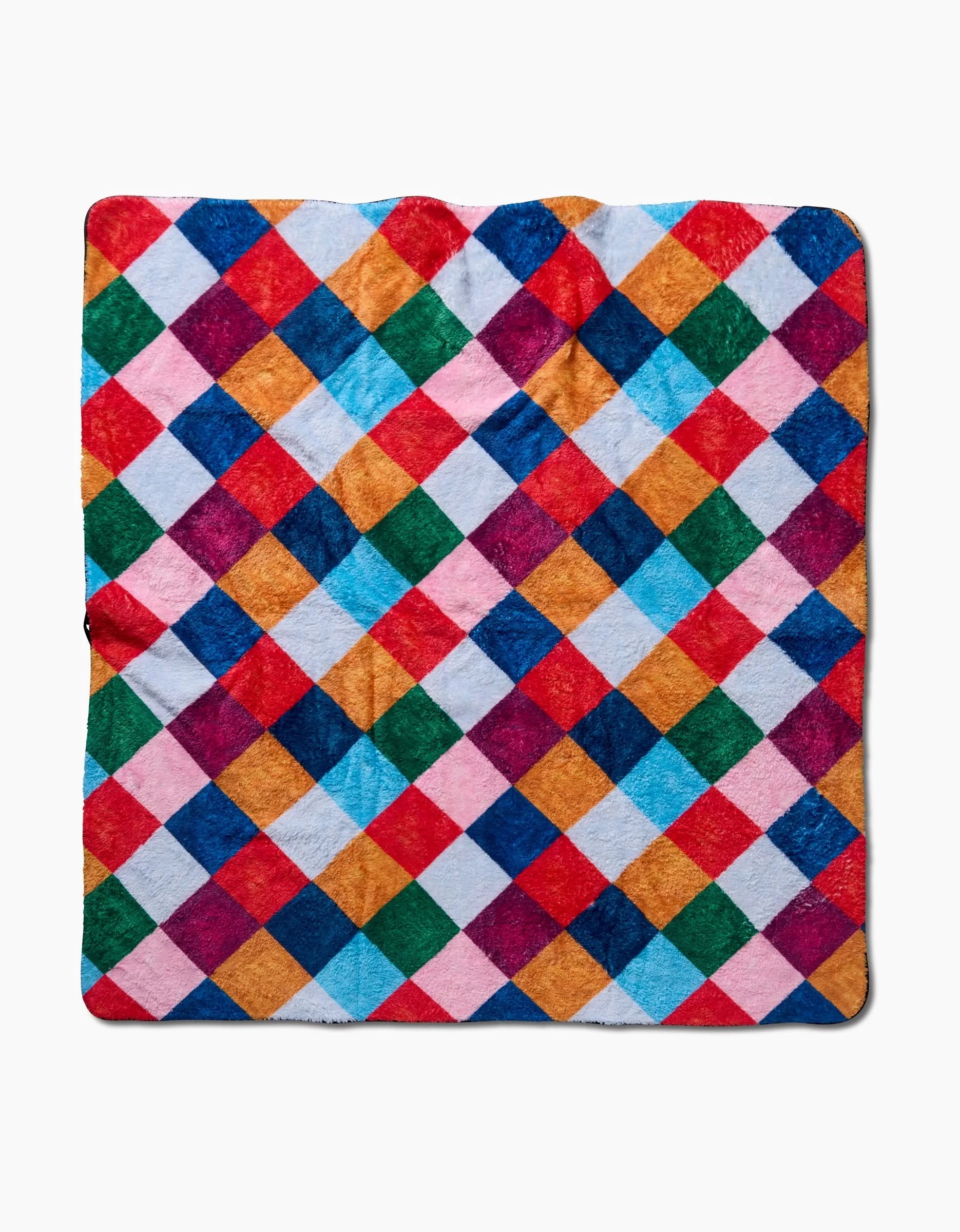 The Holiday Harlequin dog towel by Daria Solak features a diamond checkerboard pattern in red, blue, orange, green, pink, and white. Made from ultra-absorbent plush fabric, it’s soft and cozy to the touch.