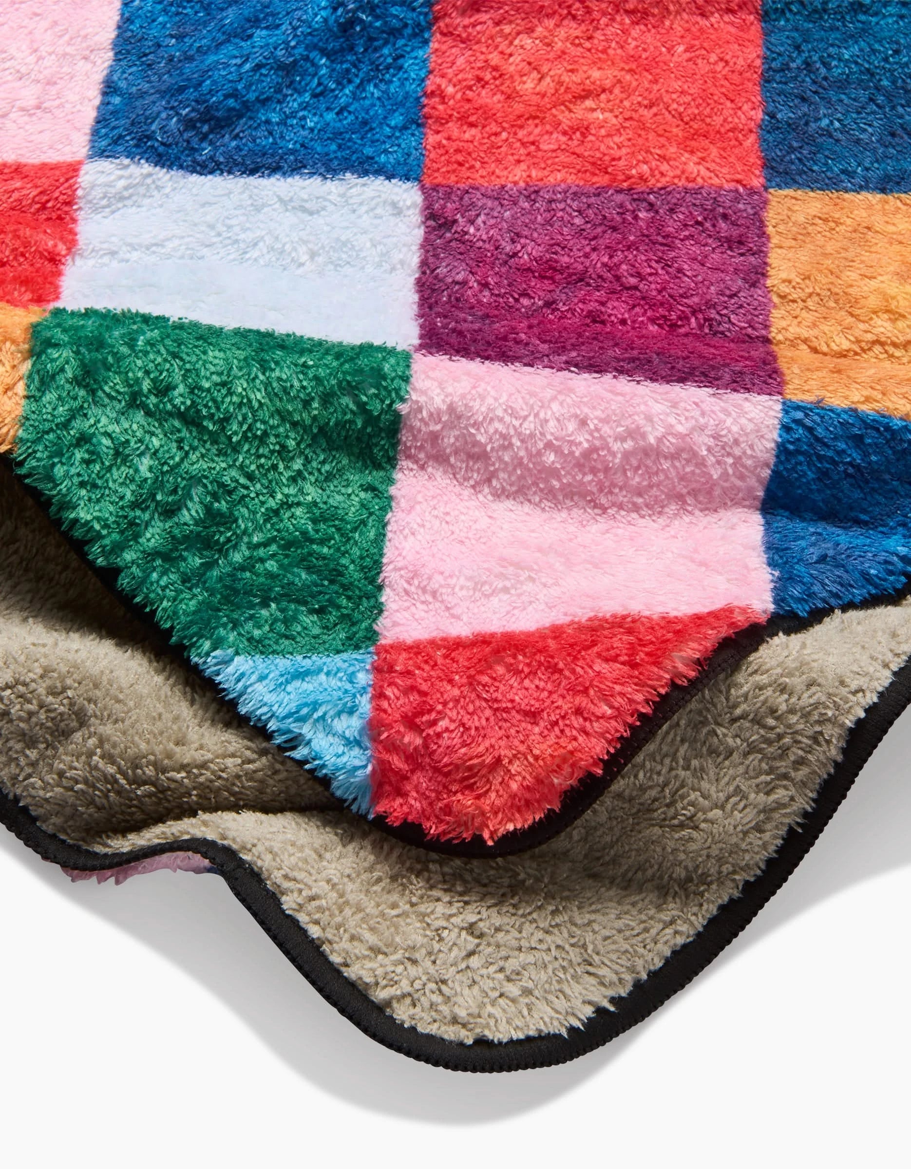 The Daria Solak Holiday Harlequin blanket features green, blue, pink, red, orange, and white checkered fleece with a soft beige sherpa lining and black trim—a colorful piece reminiscent of an ultra-absorbent dog towel.