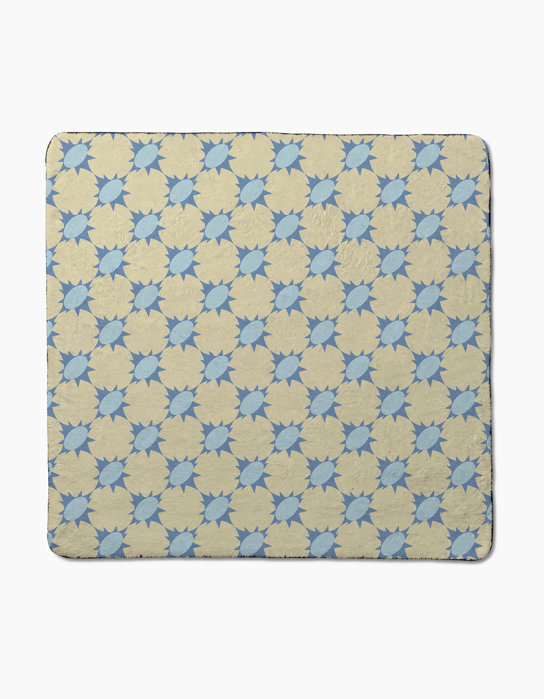 The Spiky quilt by Geometry features a repeating blue eight-pointed star pattern on beige, crafted from recycled materials. Shown laid flat on a plain white background.