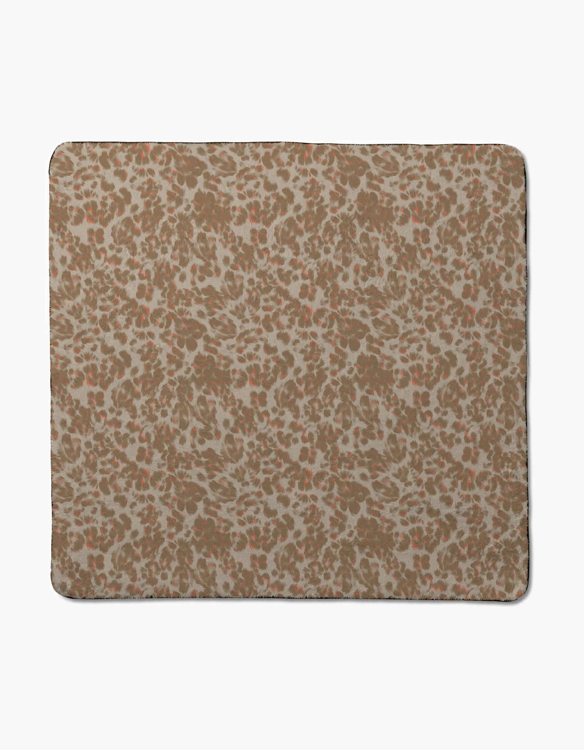 The Light Umber mat from Geometry features a brown and beige abstract leopard print on a light background, has ultra-absorbent fabric, rounded edges with a thin dark border, and an evenly repeating design over the surface.