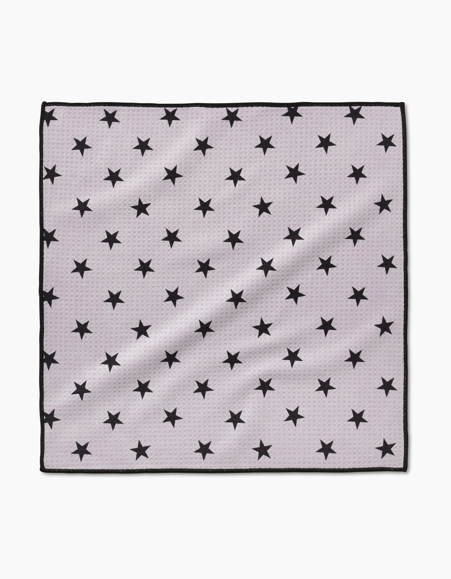 The Geometry Bark Paw Towel is a square, light gray towel made from ultra-absorbent Geoweave fabric, featuring a thin black border and a repeating pattern of evenly spaced black stars, shown laid flat on a white background.