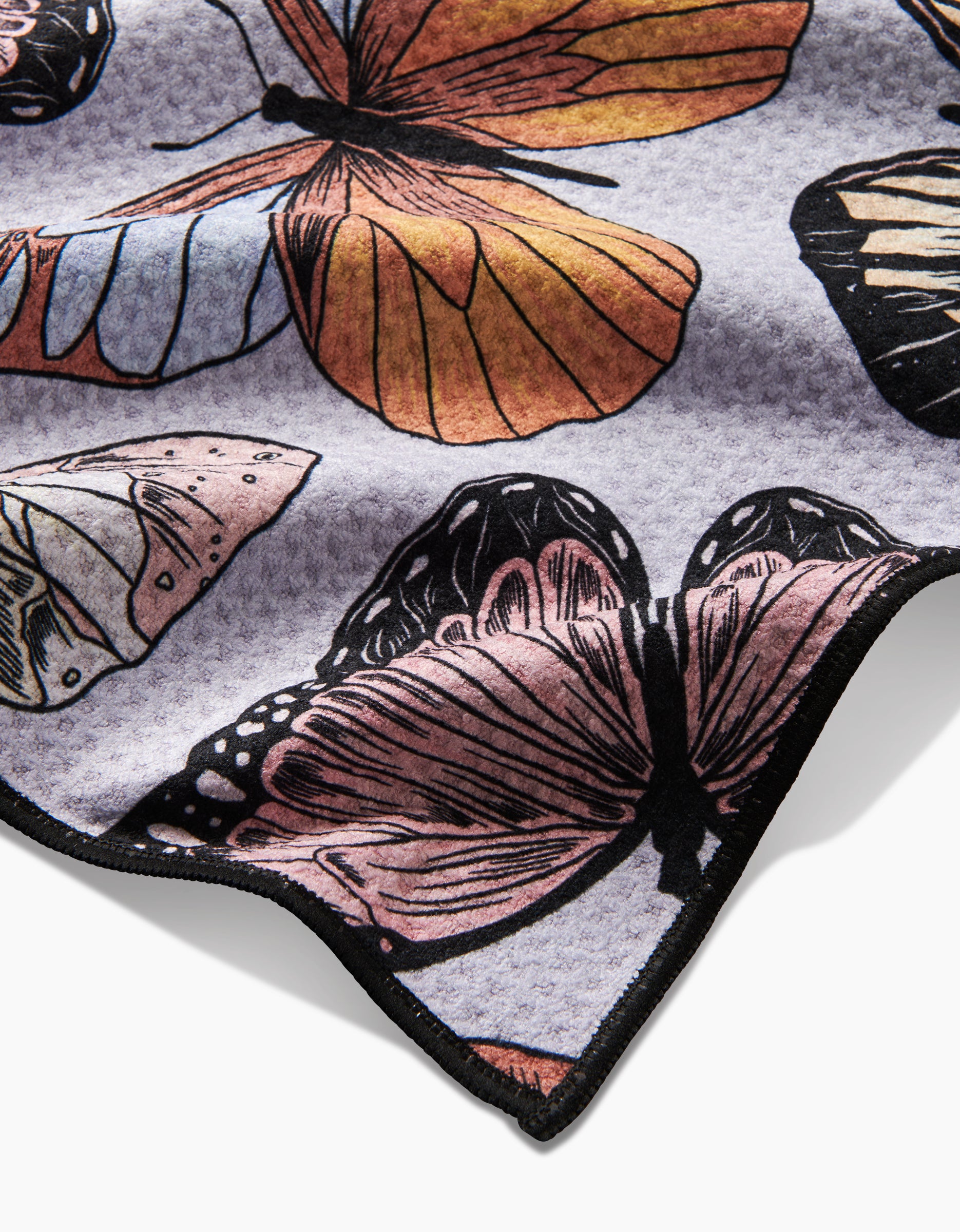 A close-up of Geometry’s Cute Butterflies towel, featuring ultra-absorbent Geoweave fabric with a colorful orange, pink, cream, and black butterfly print on a light background. The edge appears at the bottom right.