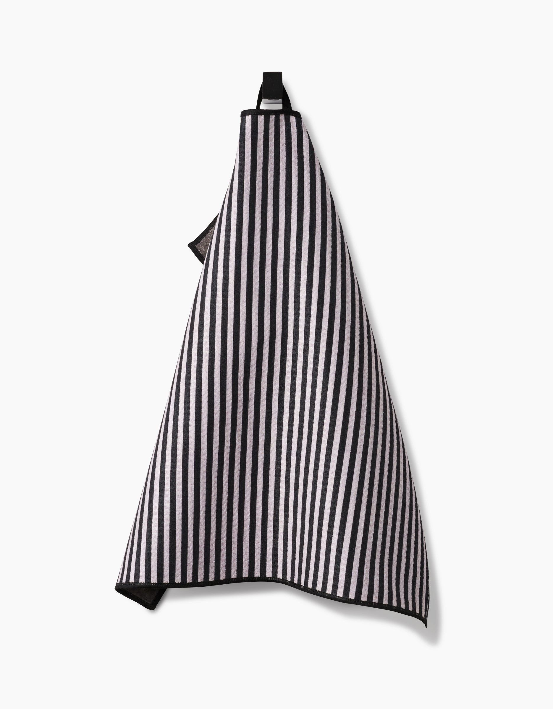 The Geometry Good Pup kitchen towel, featuring black and white vertical stripes and made from recycled materials, hangs on a hook against a plain white background.