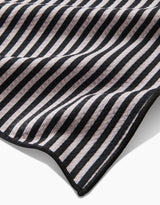 A close-up of the Good Pup Paw Towel by Geometry, made from recycled materials with black and white diagonal stripes, a wavy texture, and a stitched black edge.