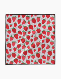 The Geometry Strawberry Sniff Paw Towel features ultra-absorbent Geoweave fabric with a repeating red strawberry and green leaf pattern on white, finished with a black border. The towel appears slightly wrinkled.