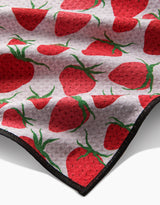 The Geometry Strawberry Sniff Paw Towel is a soft, light-gray towel made from ultra-absorbent Geoweave fabric, featuring a repeating red strawberry and green leaf pattern with a black-edged border.