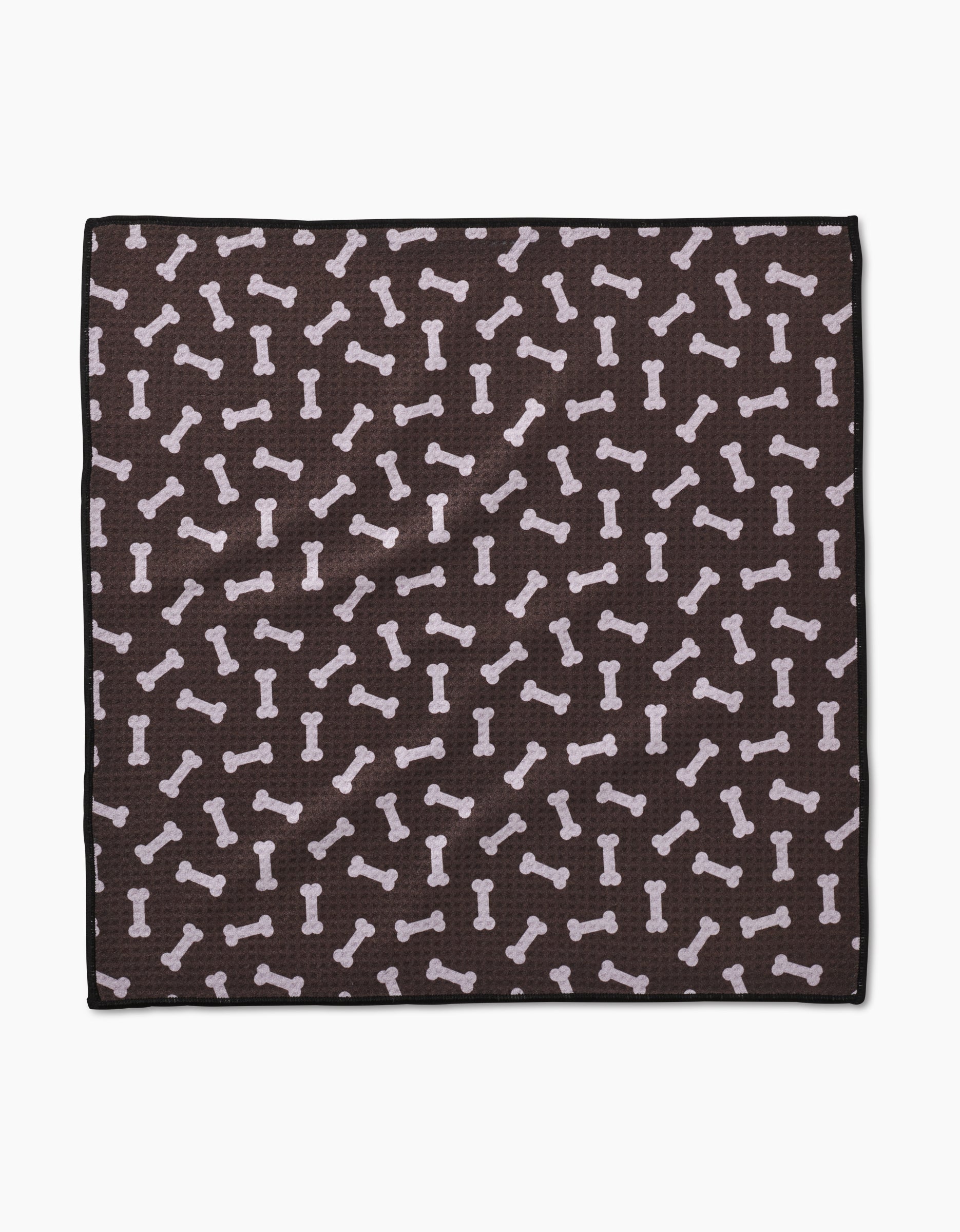 The Sweet Treats Paw Towel by Geometry is a square, dark brown towel made from recycled materials, featuring a repeating pattern of light-colored dog bones in various directions.