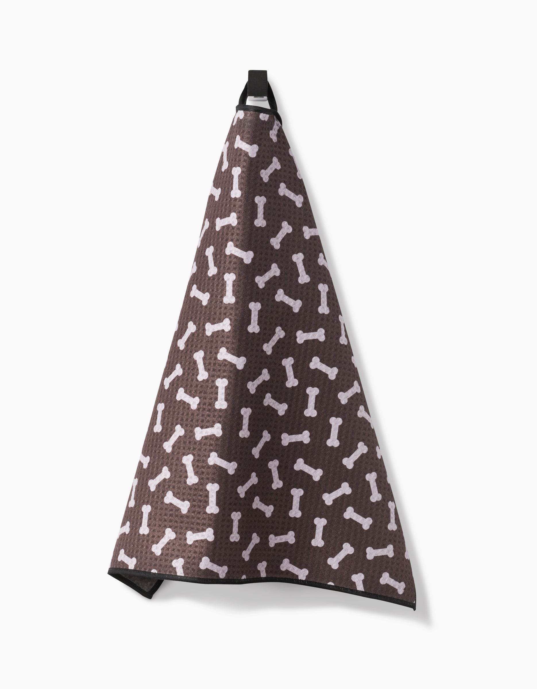 The Geometry Sweet Treats Paw Towel, made from recycled materials, features a white dog bone pattern on brown and hangs by a black loop against a plain white background.