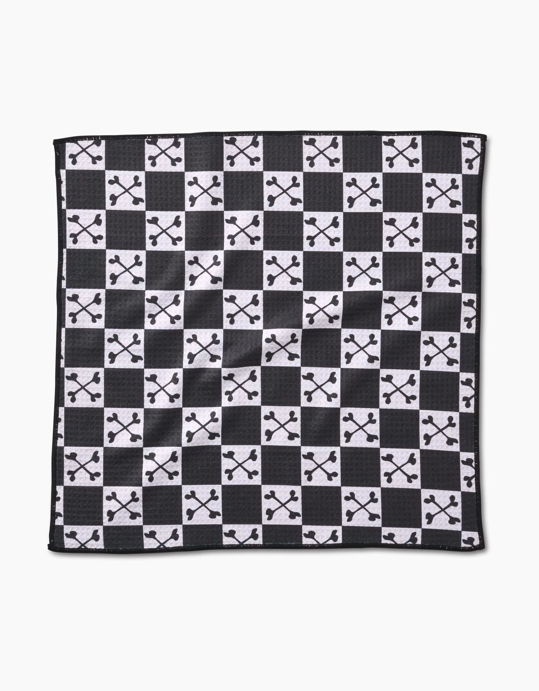 The Boneyard White Checkerboard by Charlie Rowan Designs is crafted from recycled materials and features alternating solid white squares with black squares adorned by a white abstract branched pattern.